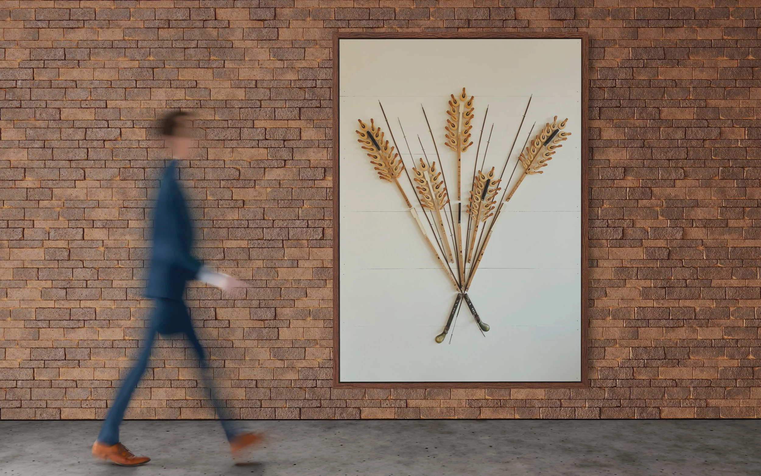 A person in a blue suit walking past a large framed art piece on a brick wall. The art piece features multiple wheat stalks made from reclaimed musical instrument components. 