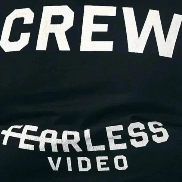Close-up of a black T-shirt with white text that reads "CREW FEARLESS VIDEO" in a bold, blocky font.