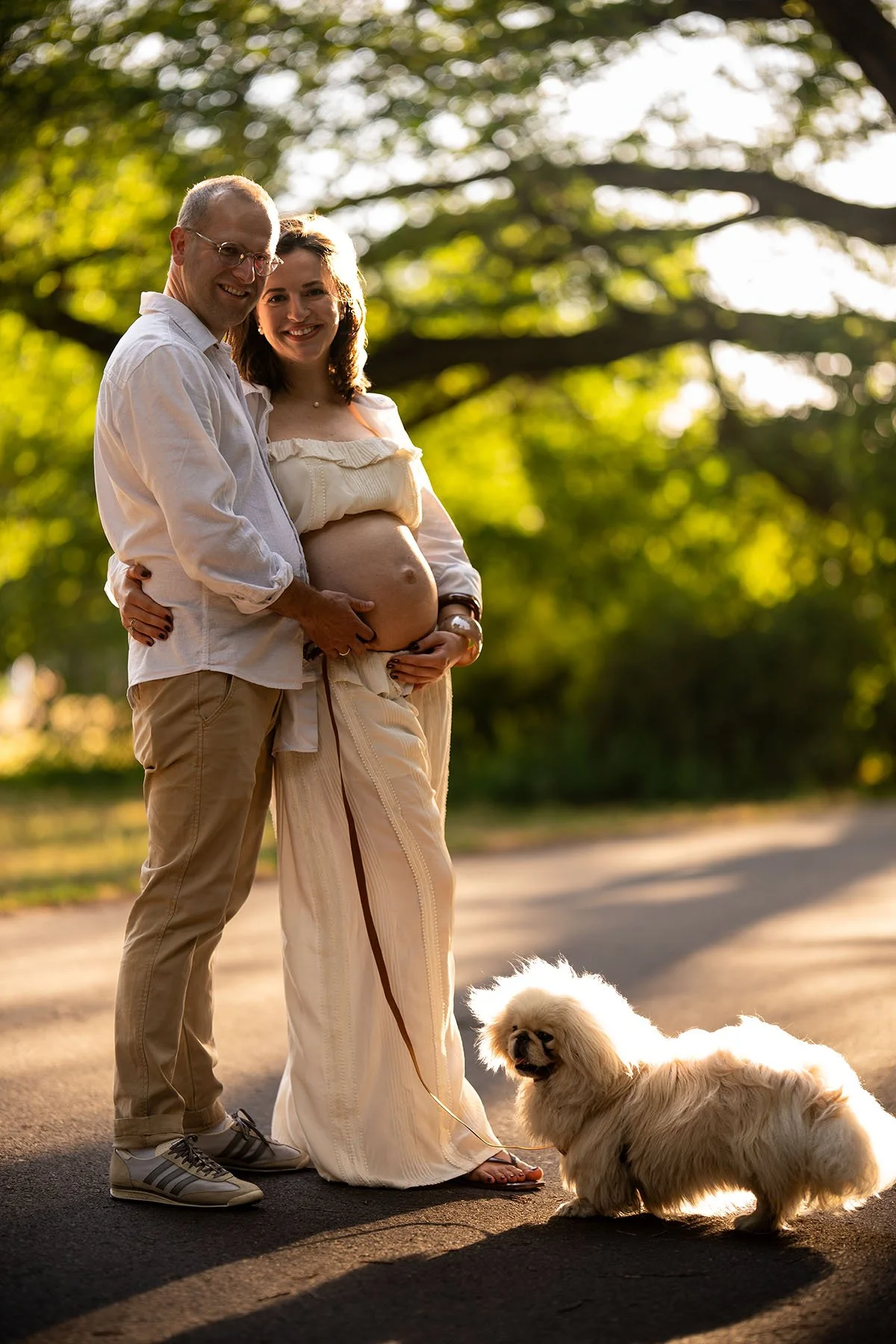 glückliches Paar mit schönem Babybauch und Hund in einem Park in Berlin im Sommer
