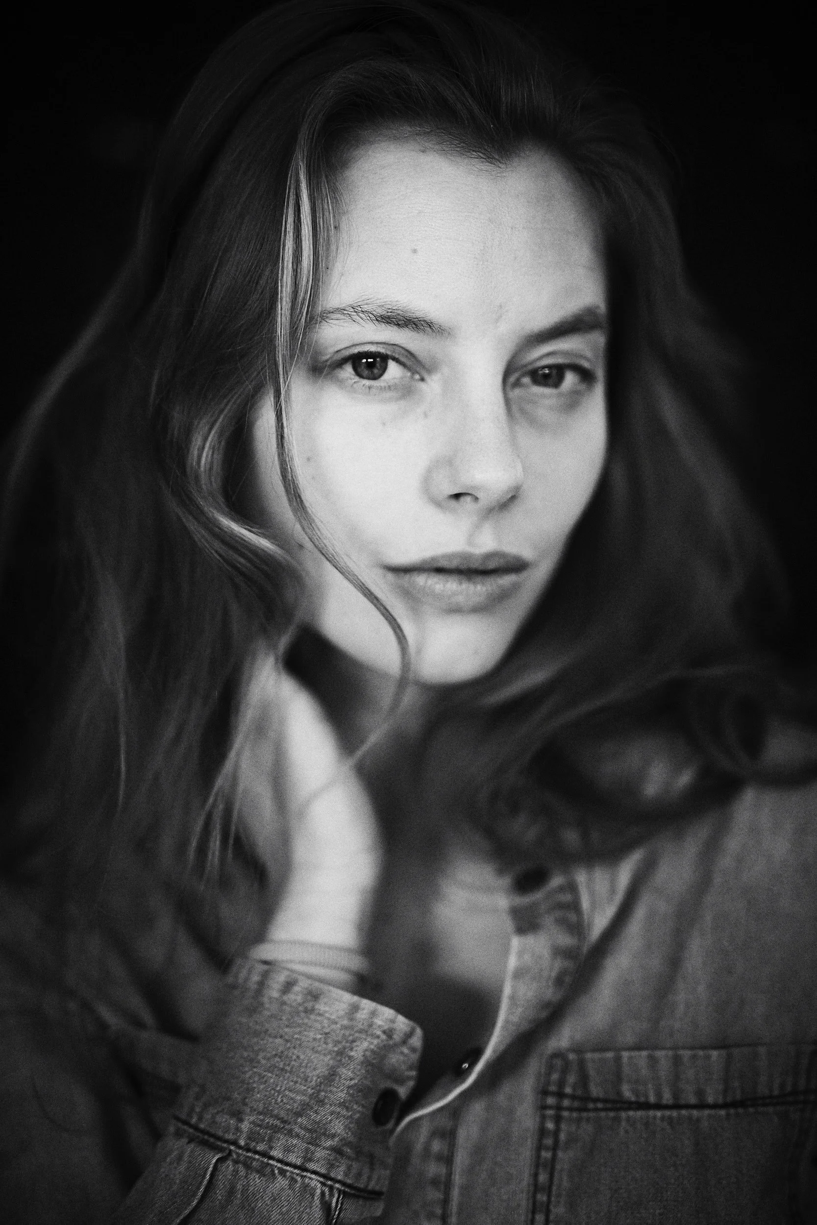 Schwarz-Weiß-Porträt einer Frau mit langen Haaren, die in die Kamera schaut.