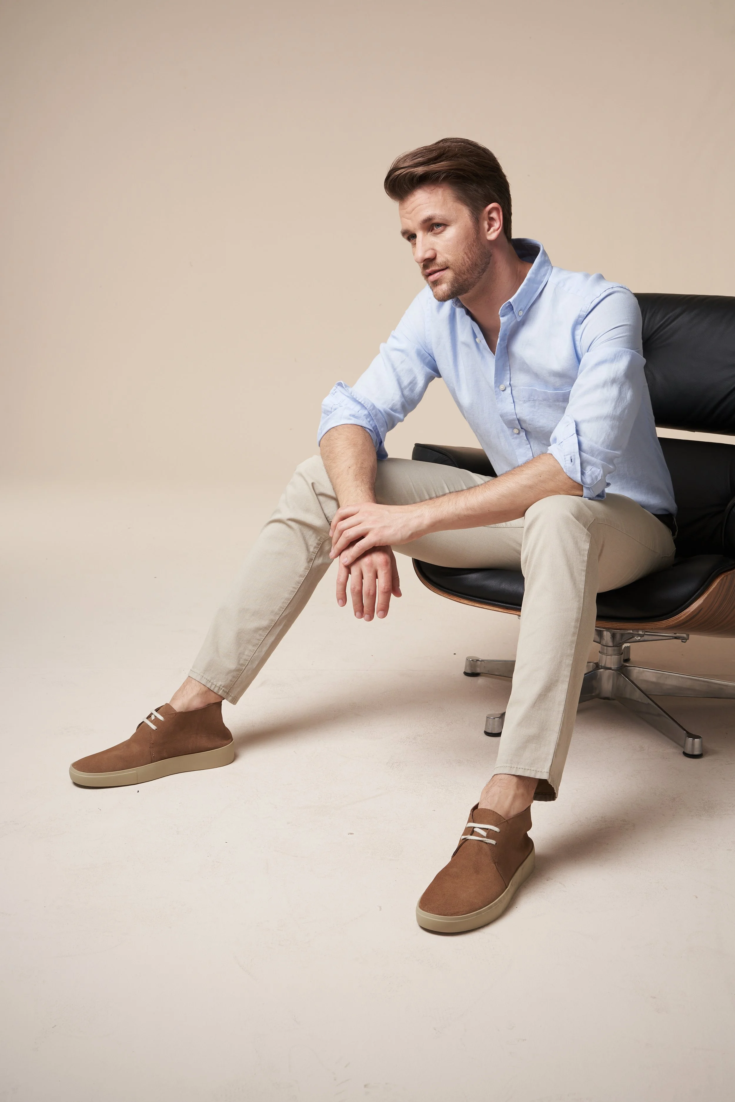 Ein Modefoto eines Mannes in einem Studioset sitzend in einem Eames Lounge Chair