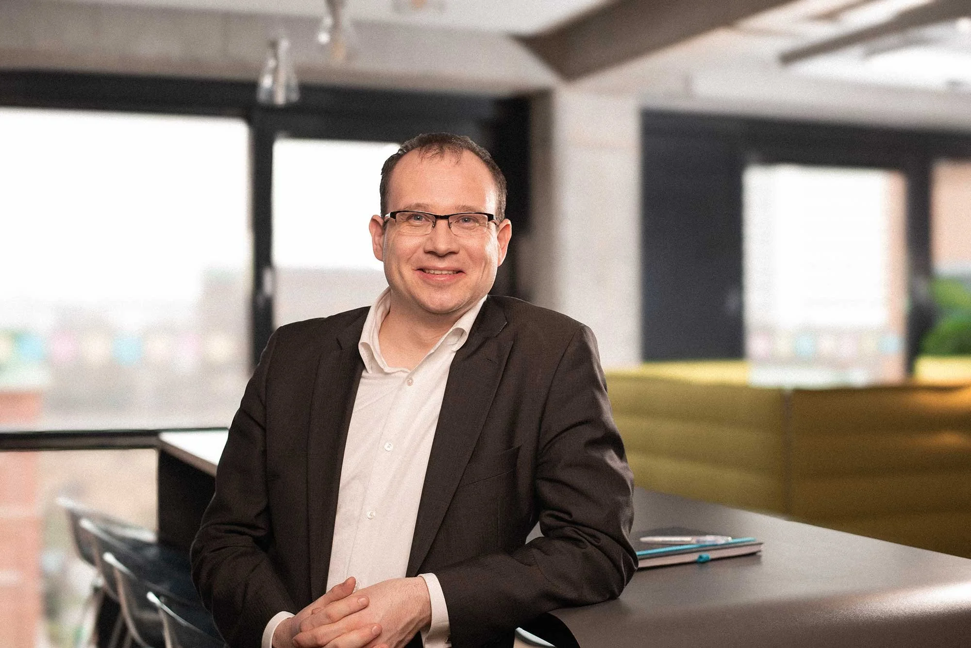 Business Foto eines Mannes in Anzug mit Brille in modernem Büro