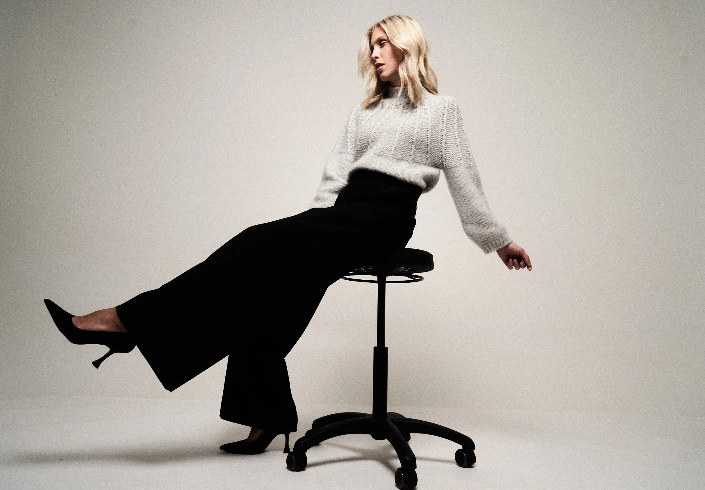 Modefotofür Jay Daze, eine junge blonde Frau sitzt auf einem Hocker