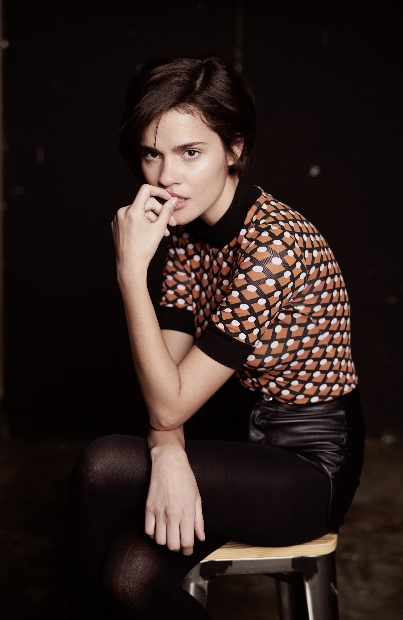 Eine junge Italienerin sitzt auf einem Barhocker in einer Studiosituation