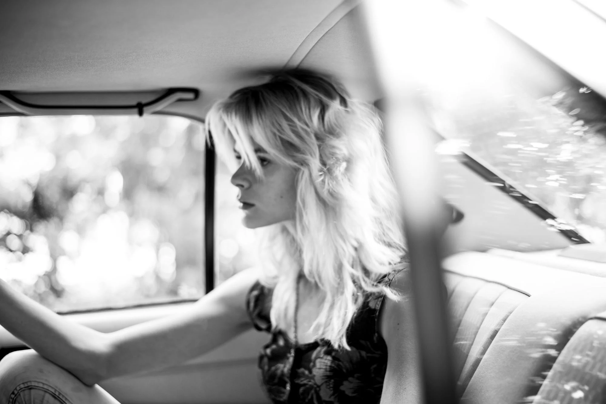 Eine junge Frau auf der Rückbank eines Mercedes 190E