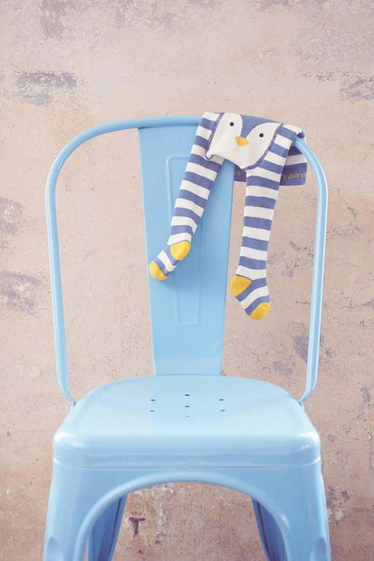 Eine bunte Baby Strumfhose hängt über einem Tolix Stuhl