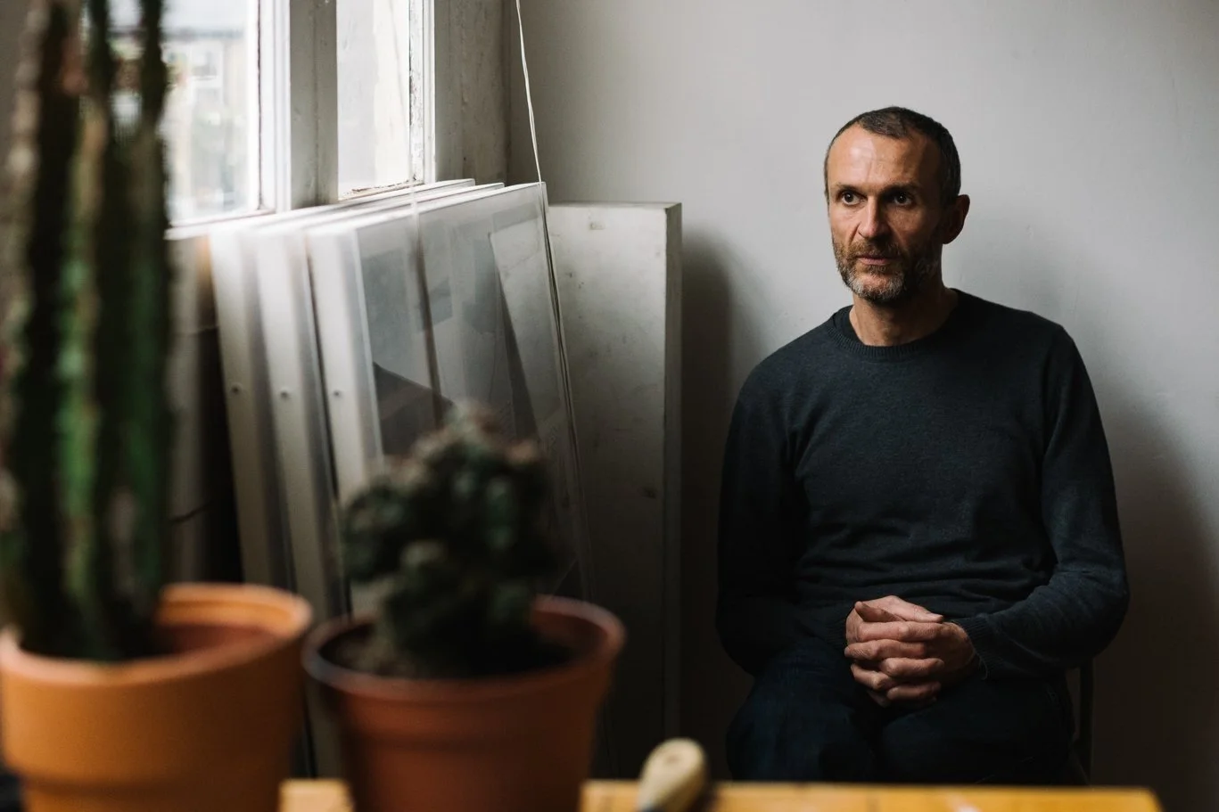 An artist in his studio, lit by window light.