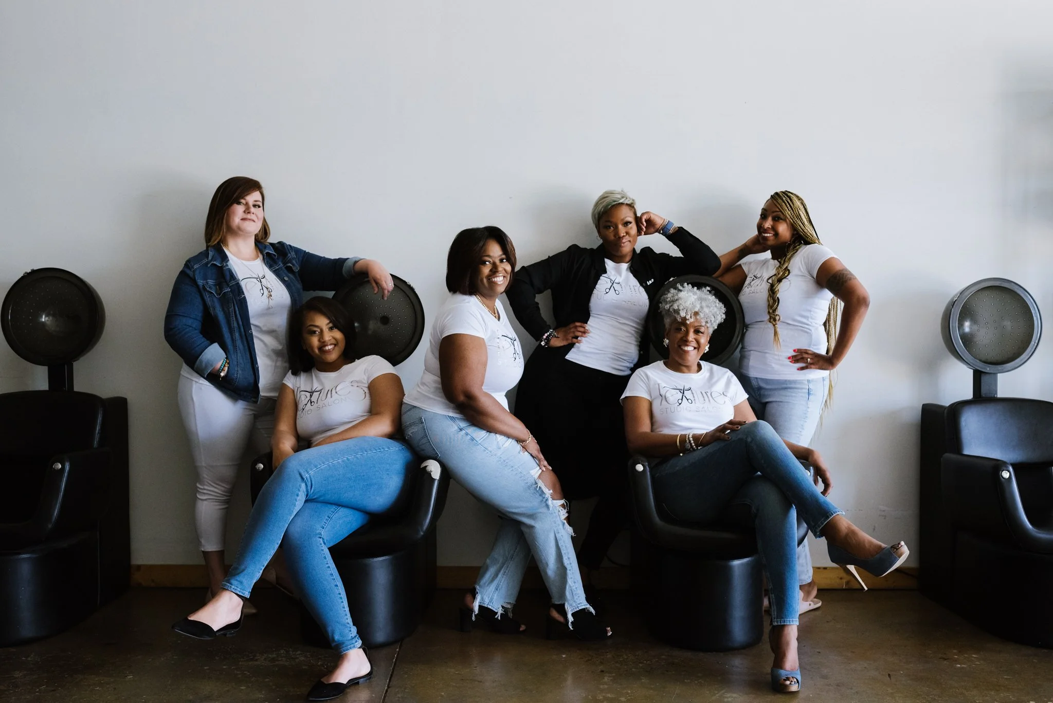 A group photo of the hair stylist team at Texture's Studio in Memphis, Tennessee. They are wearing coordinated black, white and 
 blue denim outfits.