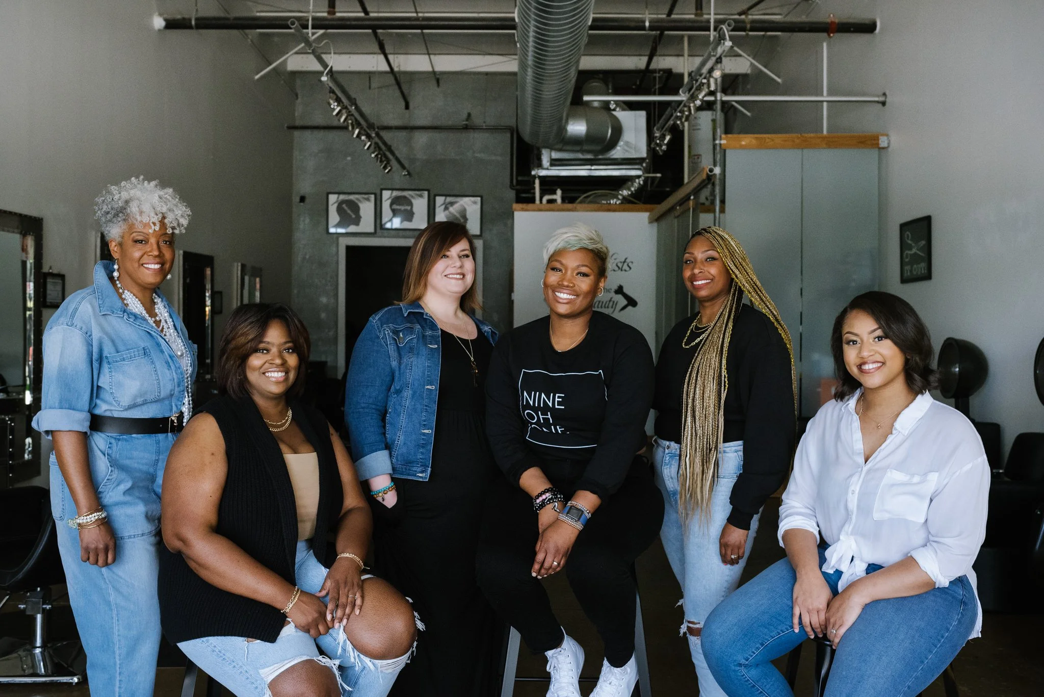 A group photo of the hair stylist team at Texture's Studio in Memphis, Tennessee. They are wearing coordinated black, white and 
 blue denim outfits.