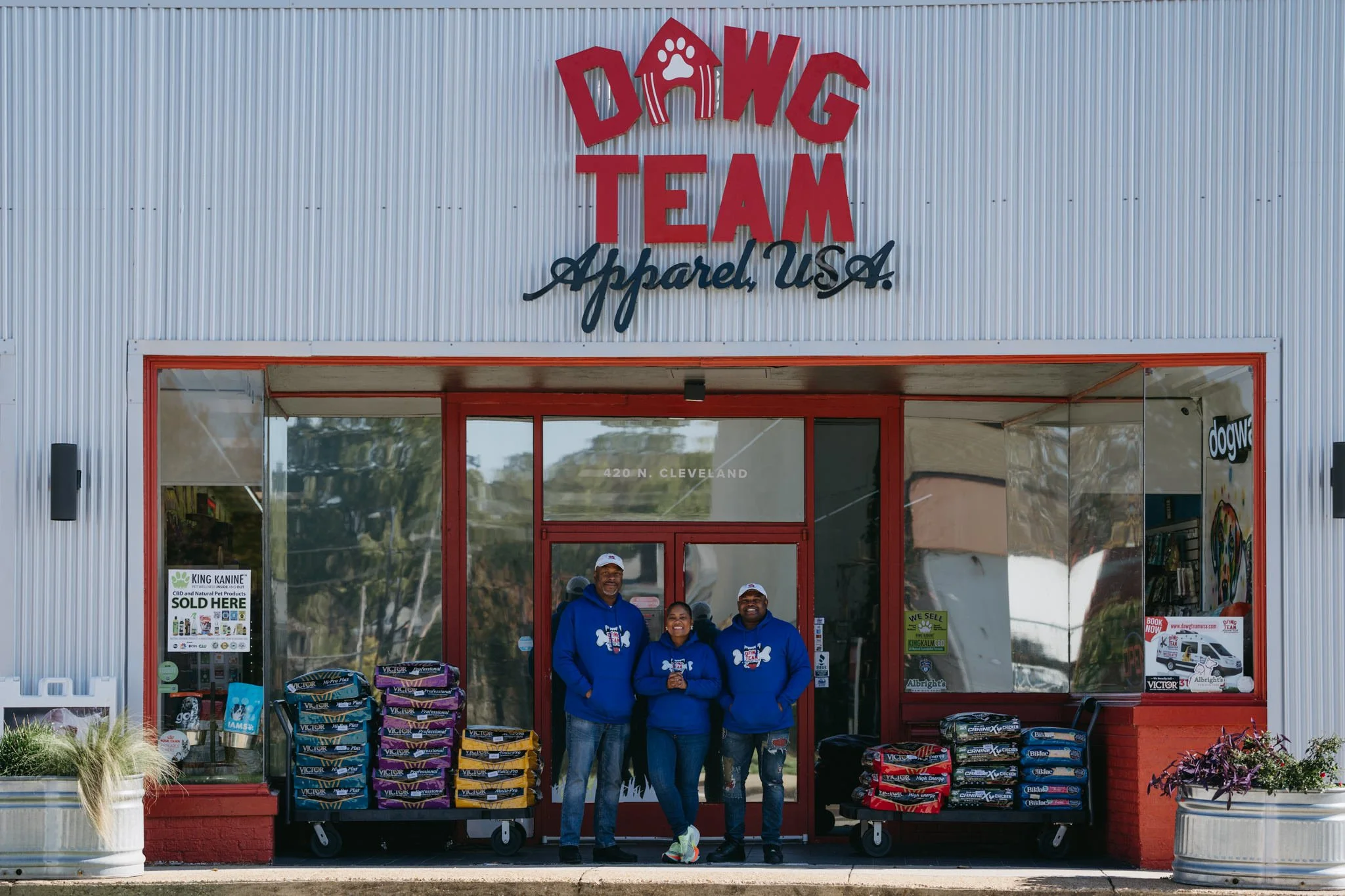 The Dawg Team owners are standing for a picture and smiling, outside the store front in Memphis, Tennessee. They are all wearing matching blue company hoodies.