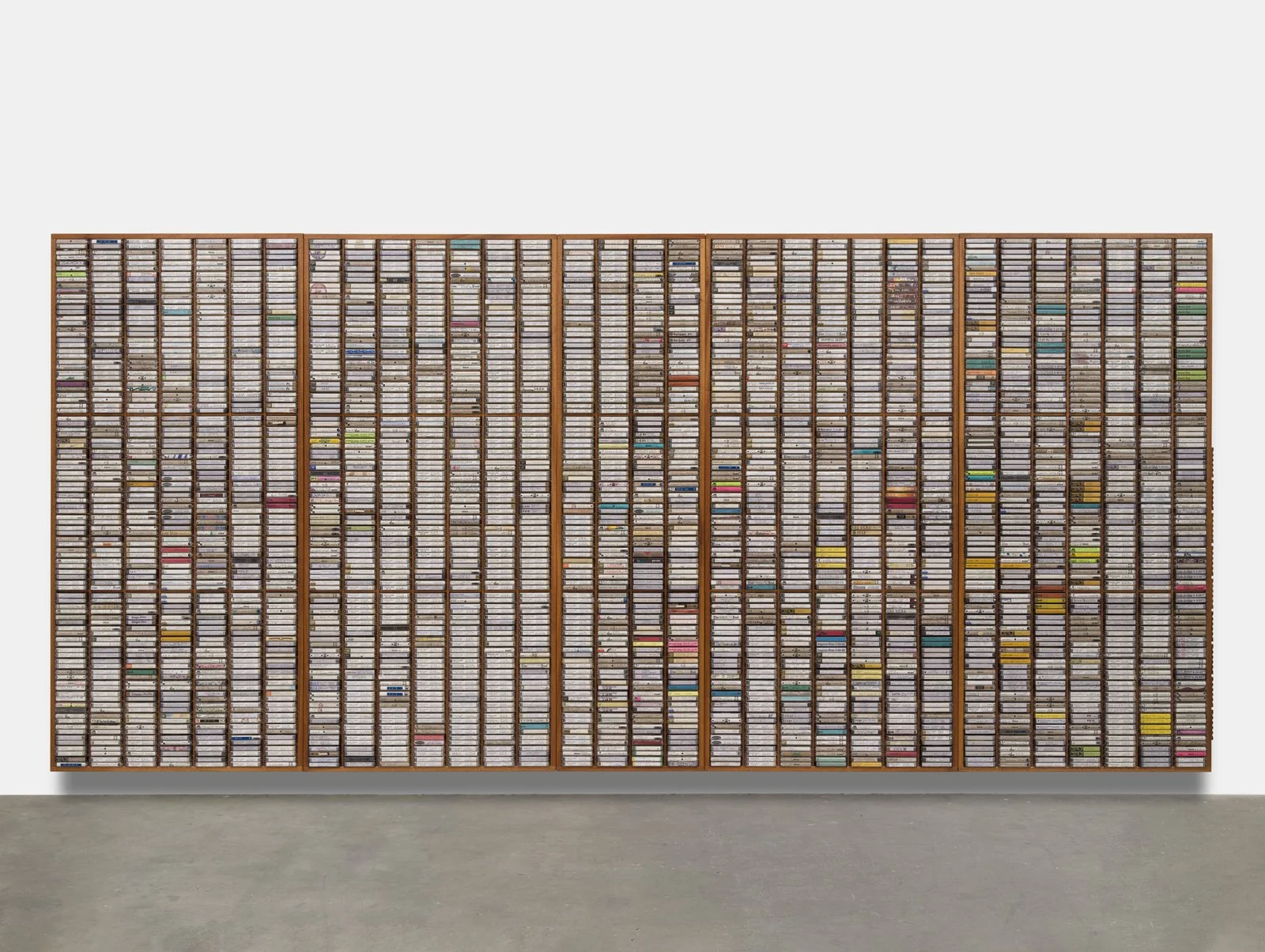 9th Gen, 2010-2022. Mahogany shelving units, 3072 audio cassettes of Grateful Dead live performances in chronological order from 1965 to 1995, plastic tape cases, ink and marker on paper, oil-based enamel, 73.875 x 157.75 x 3.5 in