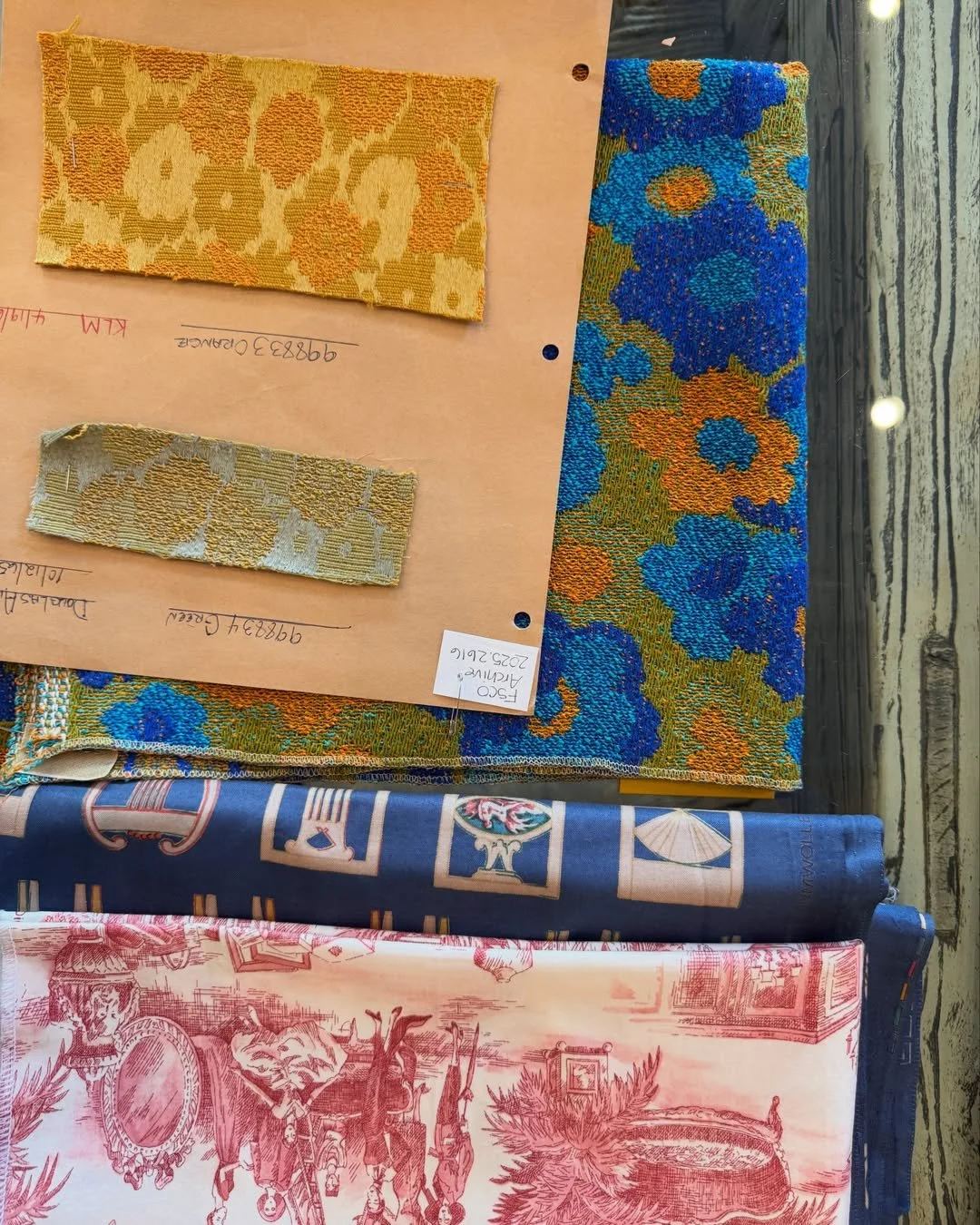 Schumacher archival textile samples with yellow floral patterns, blue and green flowers, and red scenic toile.