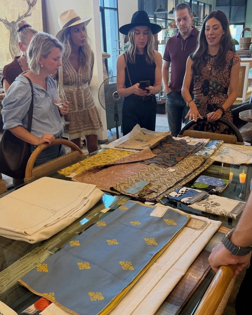 Designers reviewing Schumacher archival textiles on a table at Litt Concept House, including blue floral and gold patterned fabrics.