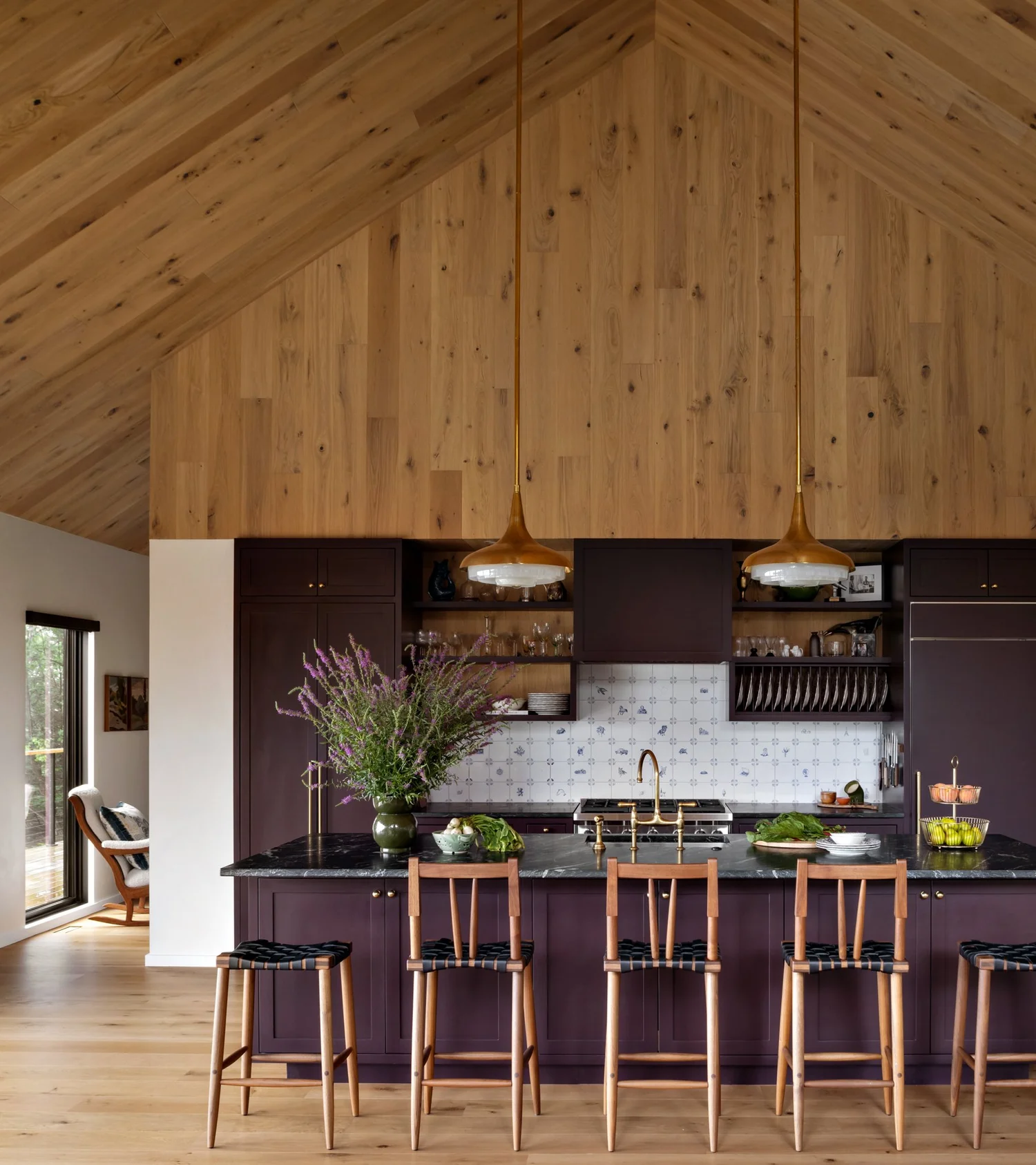 Kitchen with a vaulted wood ceiling, plum island, brass pendant lights, wood bar stools, and patterned backsplash.