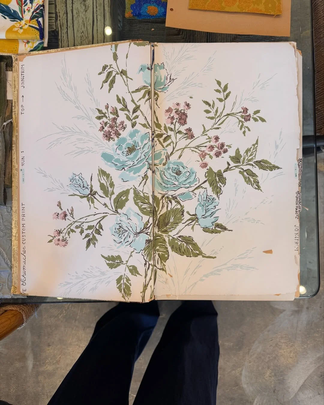 Schumacher archival floral design with pale blue roses, green leaves, and pink flowers on a cream ground.