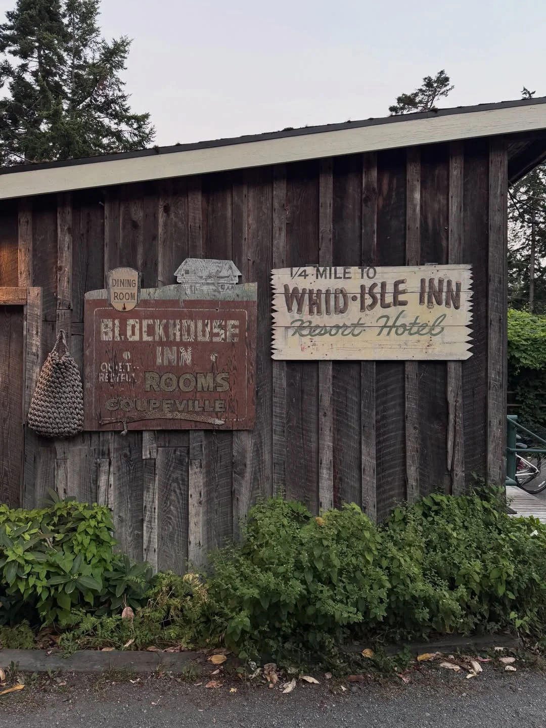 Weathered timber wall at Captain Whidbey Inn with vintage Blockhouse Inn and Whid-Isle Inn signs.