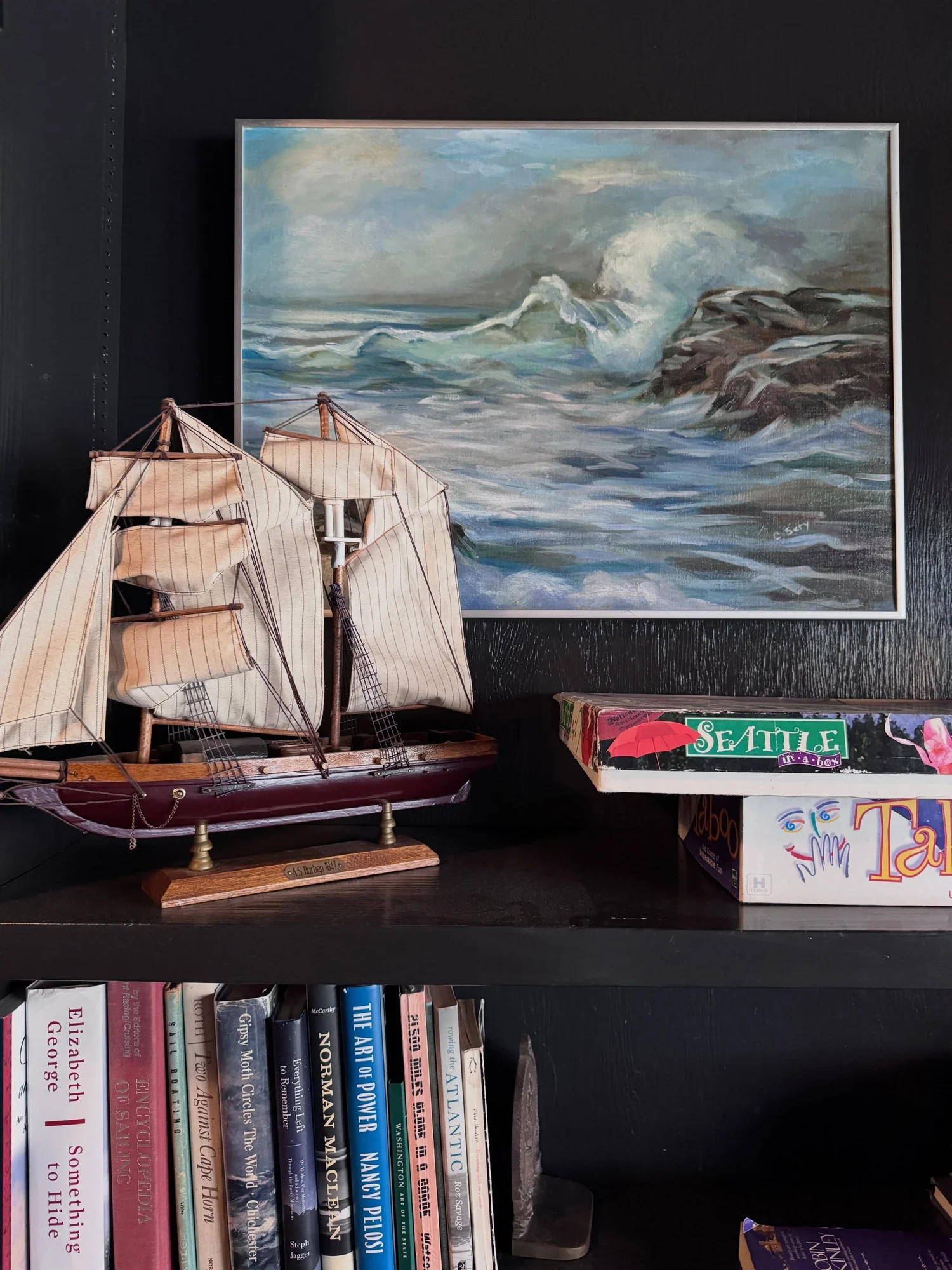 Vintage sailing ship model, framed seascape, and books displayed at Captain Whidbey Inn.