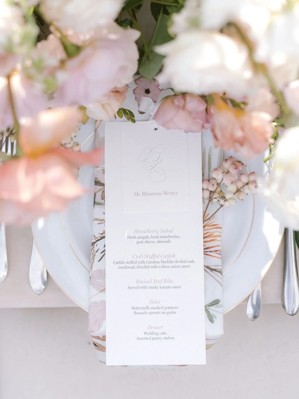 A clean and elegant typography menu design on white paper with a calligraphy monogram