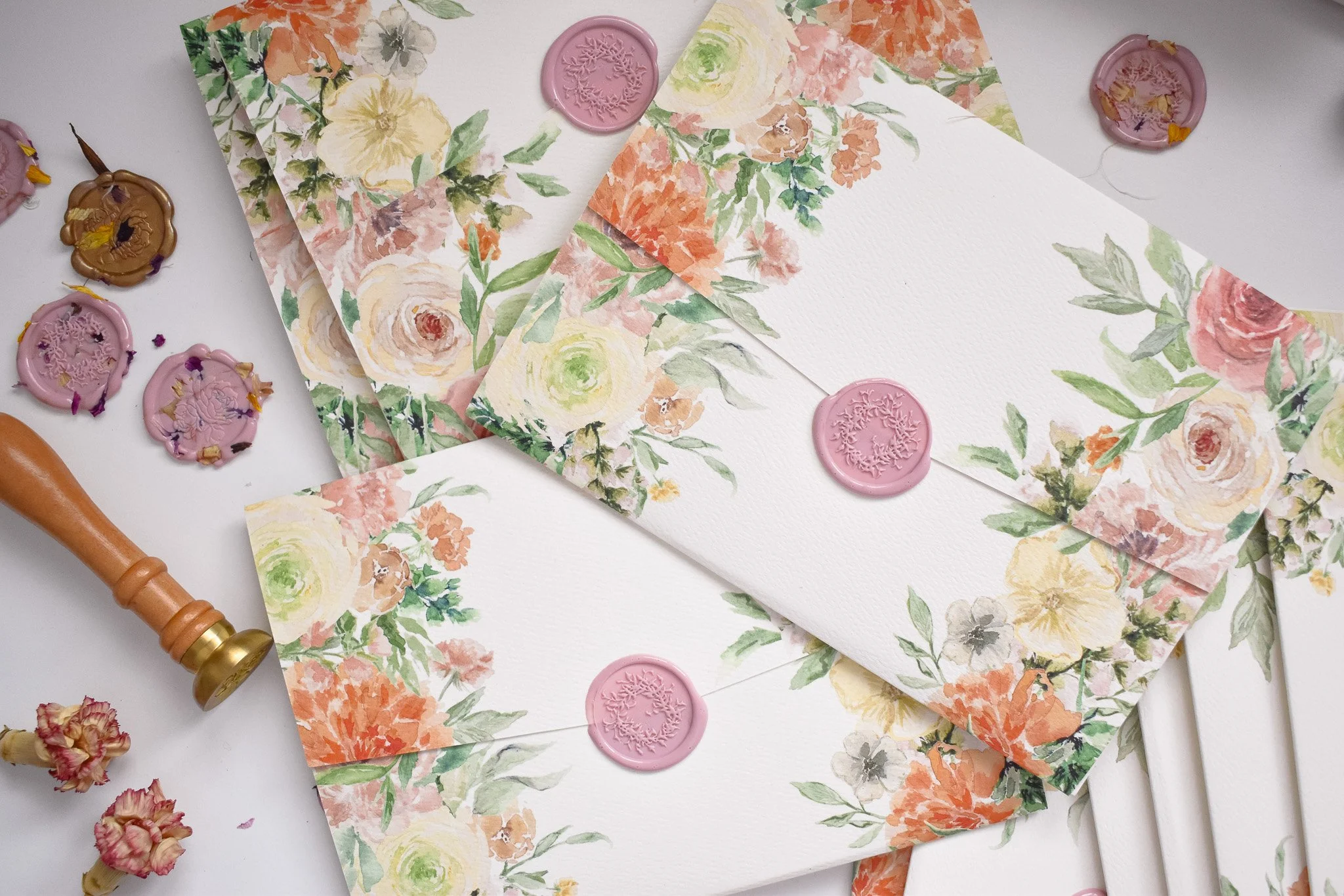 Colorful watercolor floral art on a folder that is sealed with a pink laurel stem wax seal.