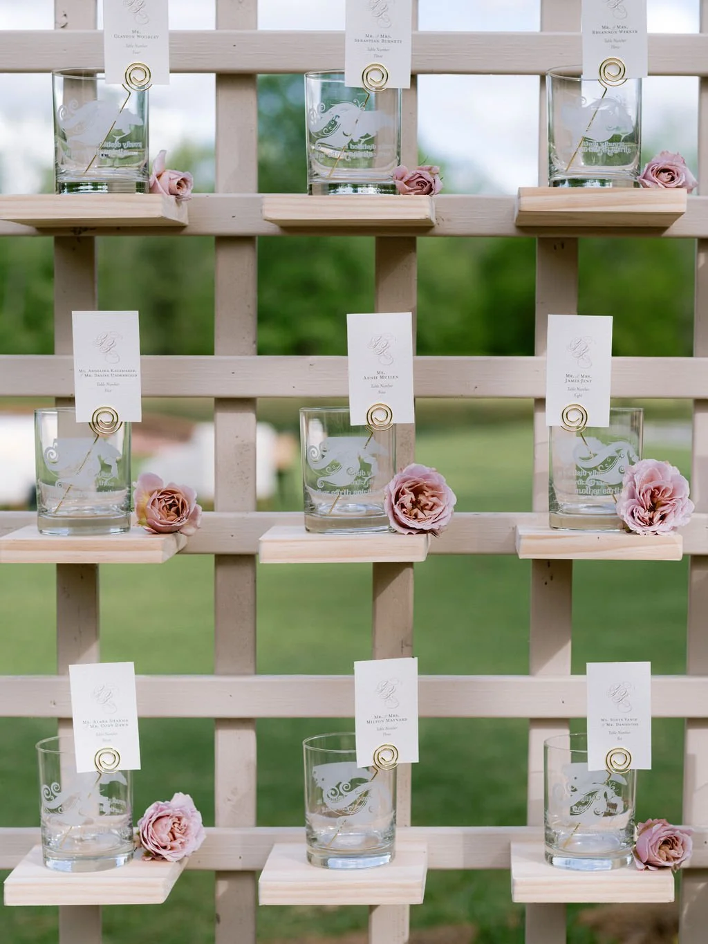 clean and elegant typography with guest names on individual cards held by a gold pick inside a custom etched clear glass on a display trellis