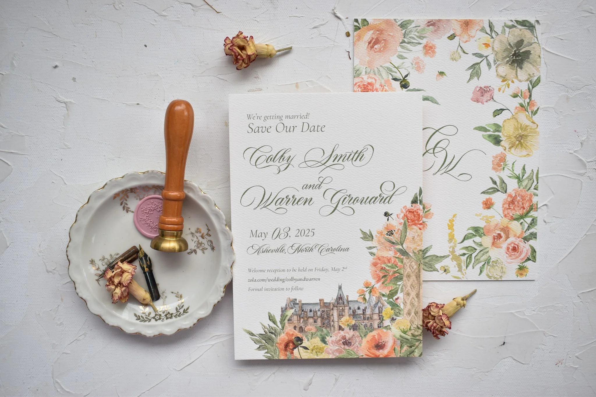 A wedding save the date on white paper featuring the Biltmore Estate with calligraphy and custom watercolor flower art