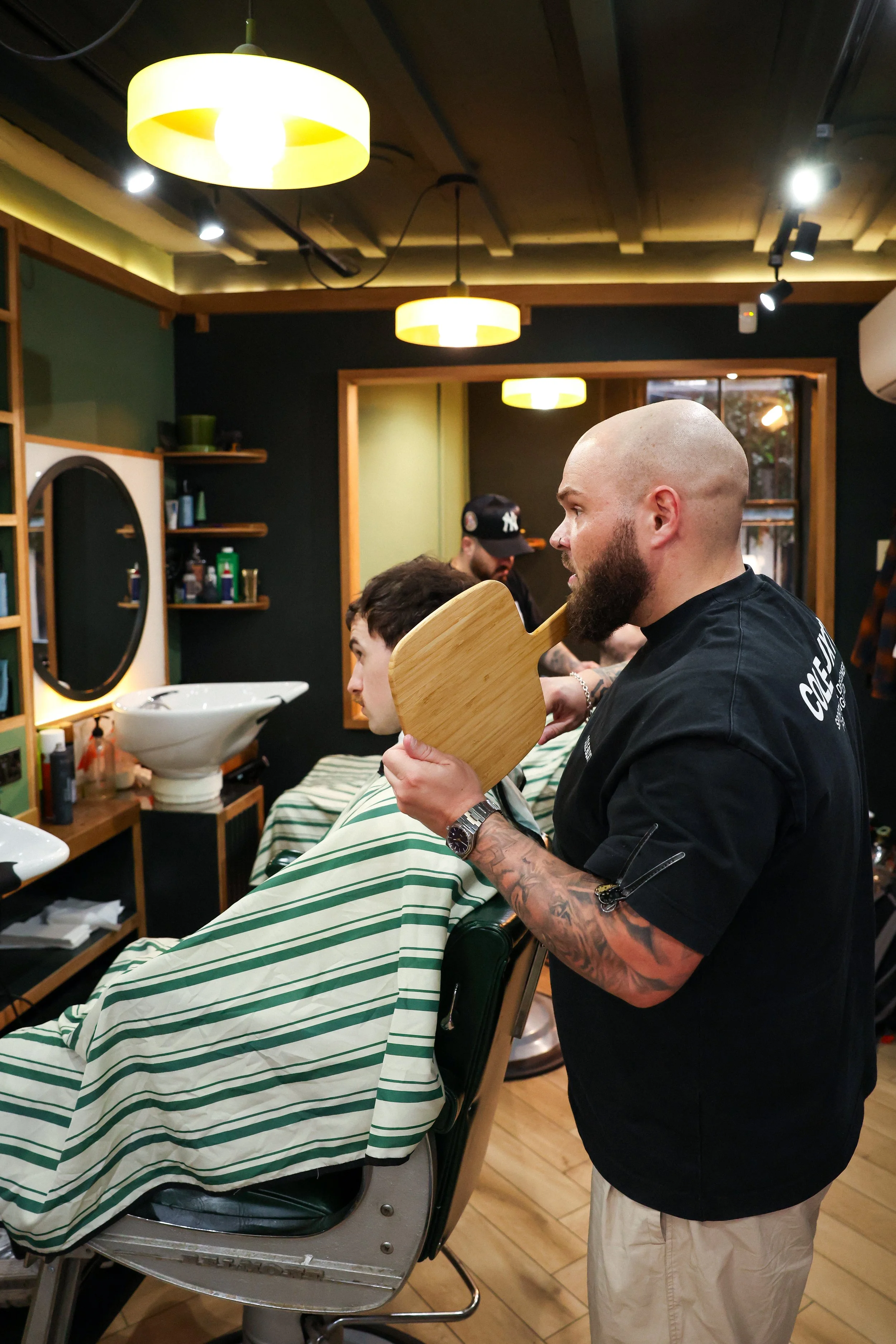 Fella barber showing client back of hair in mirror