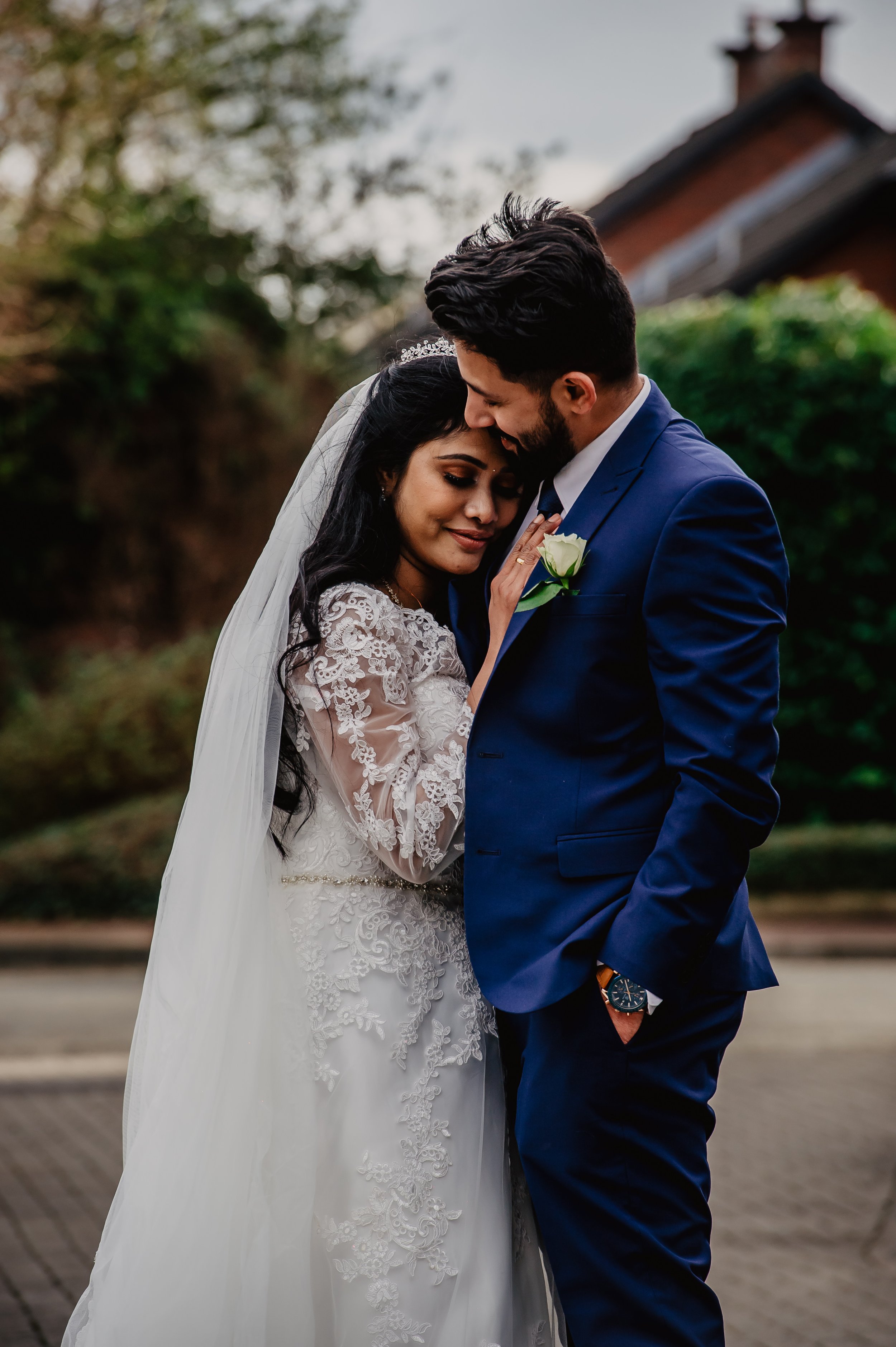a bride cuddles into her grooms chest outside during their photographs