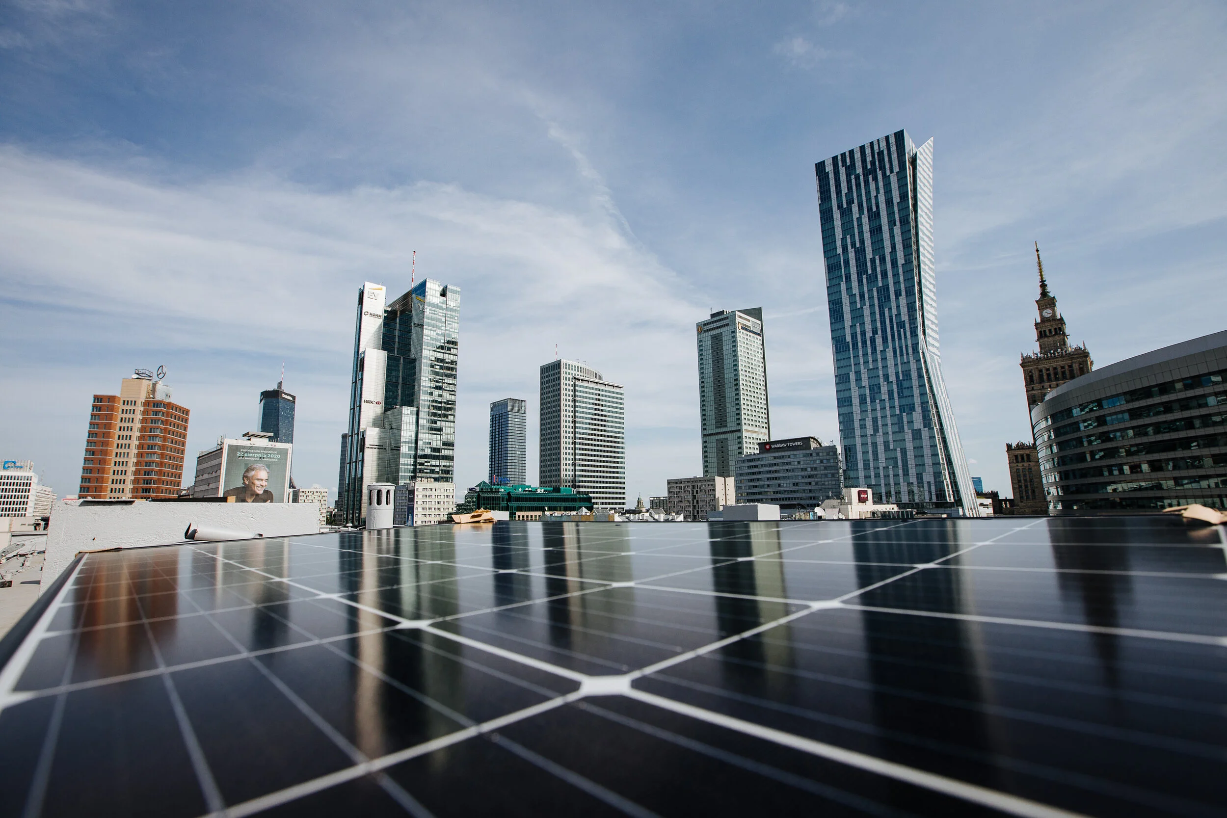 City skyline with tall modern skyscrapers and a rooftop solar panel in the foreground.