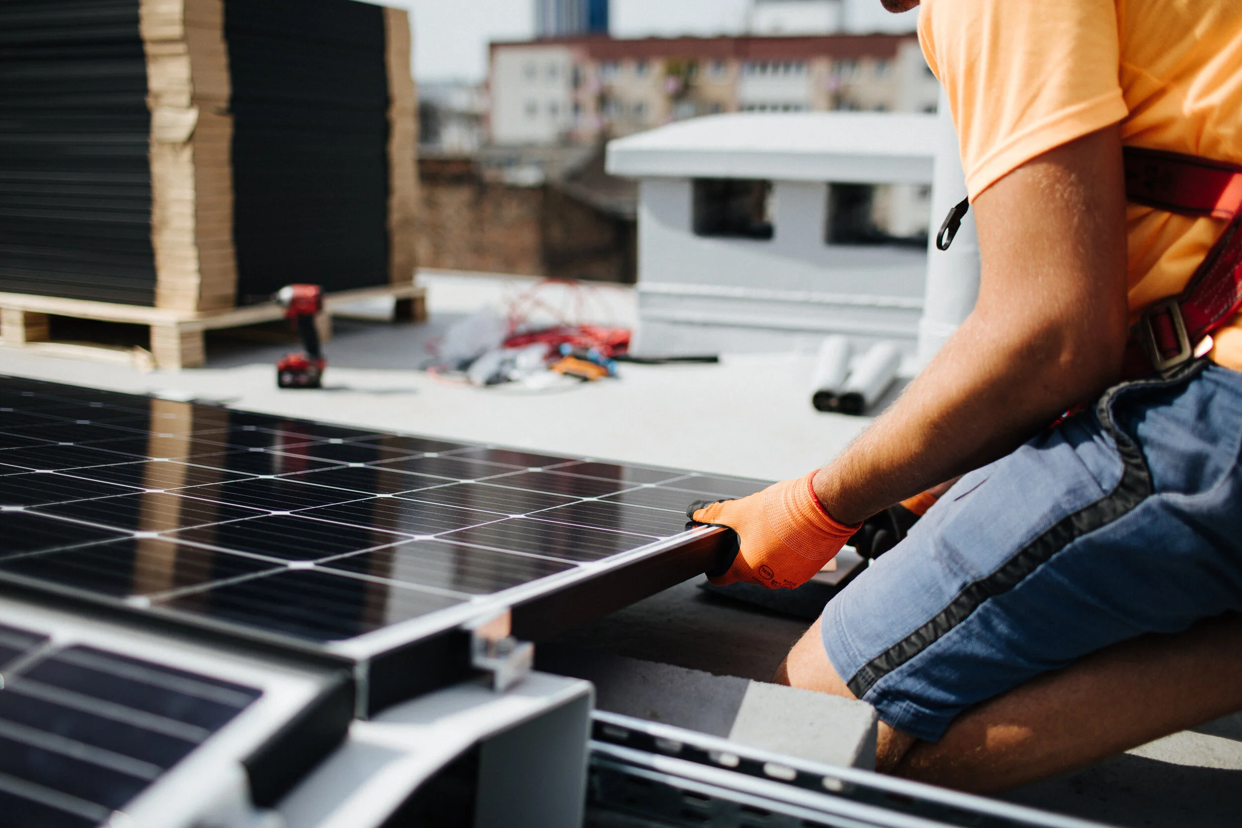 Person installing solar panels on a rooftop using tools and wearing work gloves.