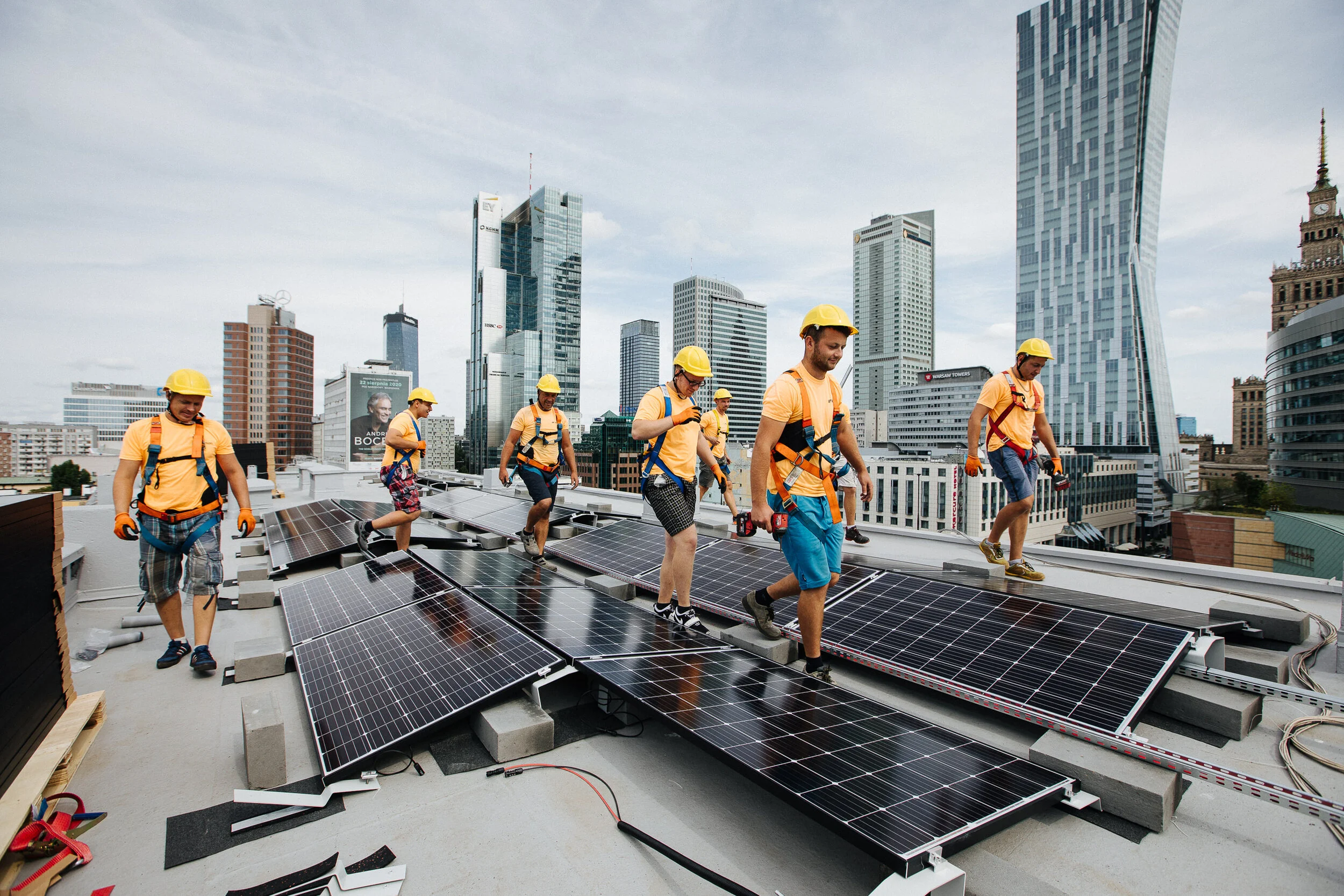 Workers installing solar panels on a city rooftop with skyscrapers in the background.