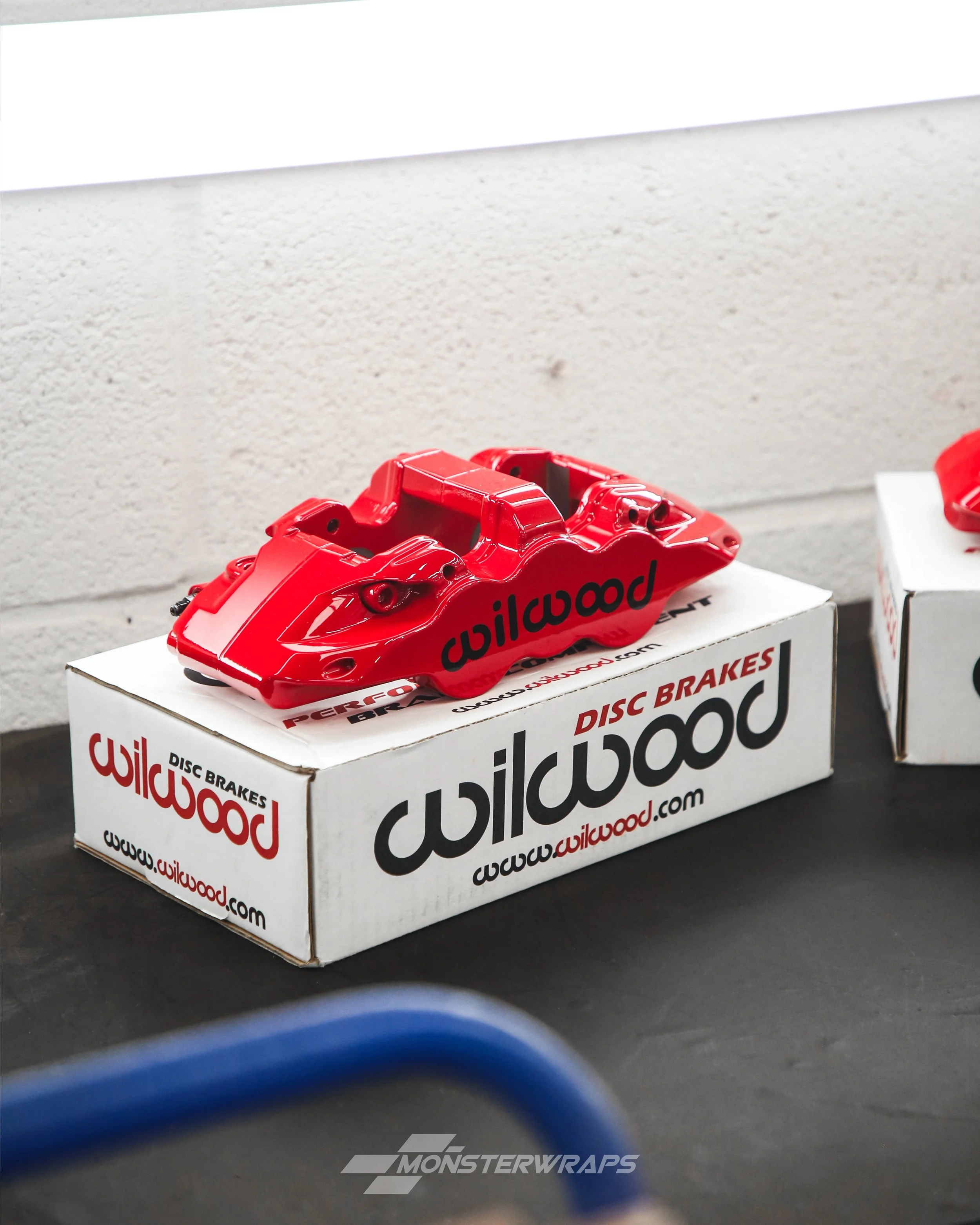 wilwood 4 piston brake calipers painted in gloss performance red with gloss black wilwood decals applied on top
