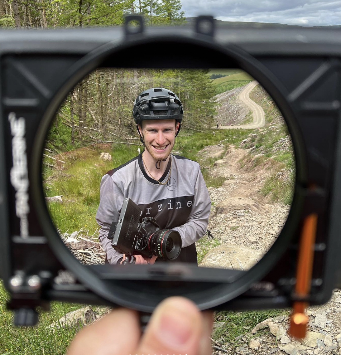Filmmaker Liam Moss holding a Red Raptor camer. Liam is where a mountain bike helmet and it in the Scottish hillsa
