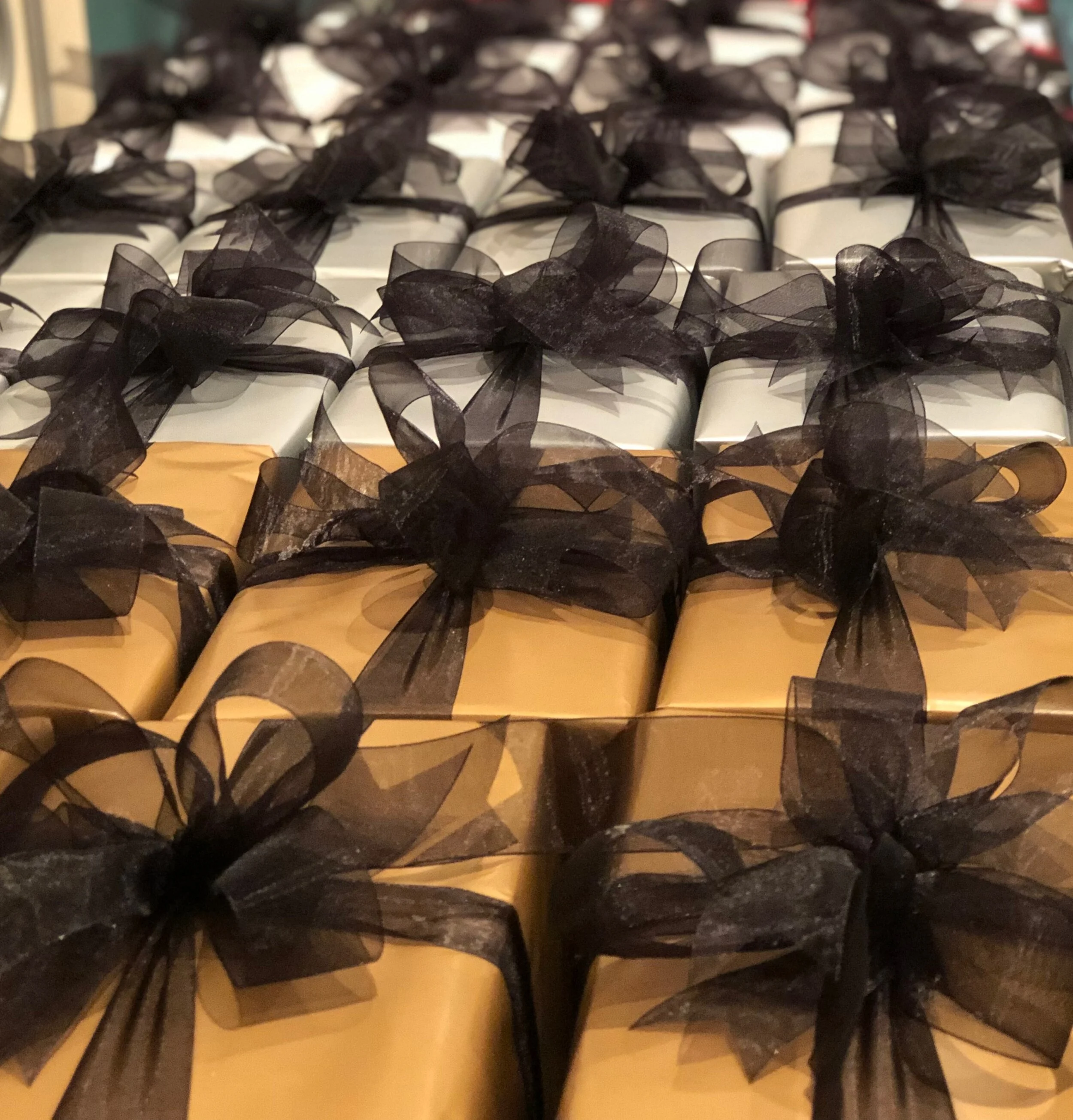 rows of gifts wrapped in gold and silver paper with black bows