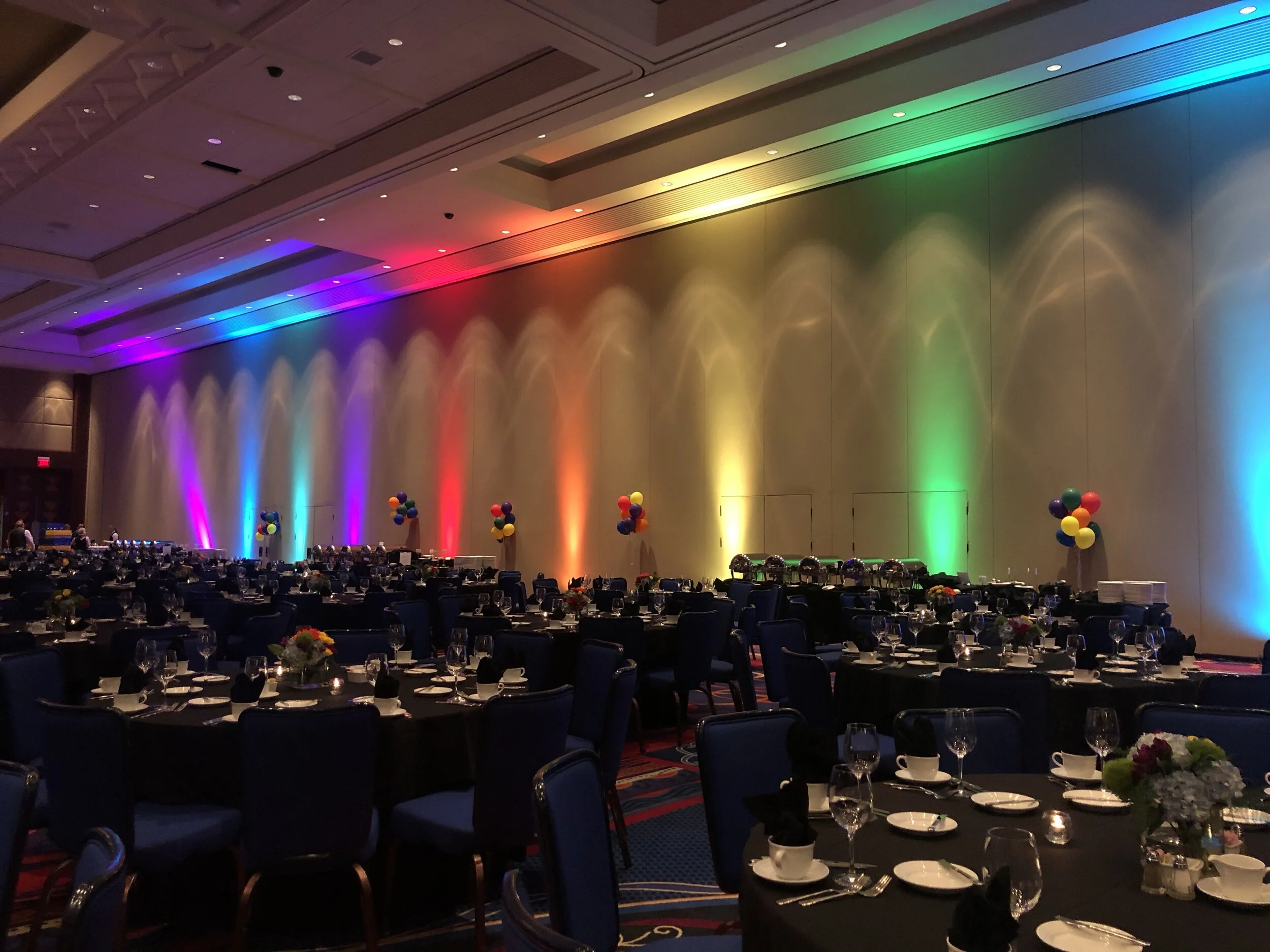 ballroom set for awards program lighting on the wall in the rainbow colors