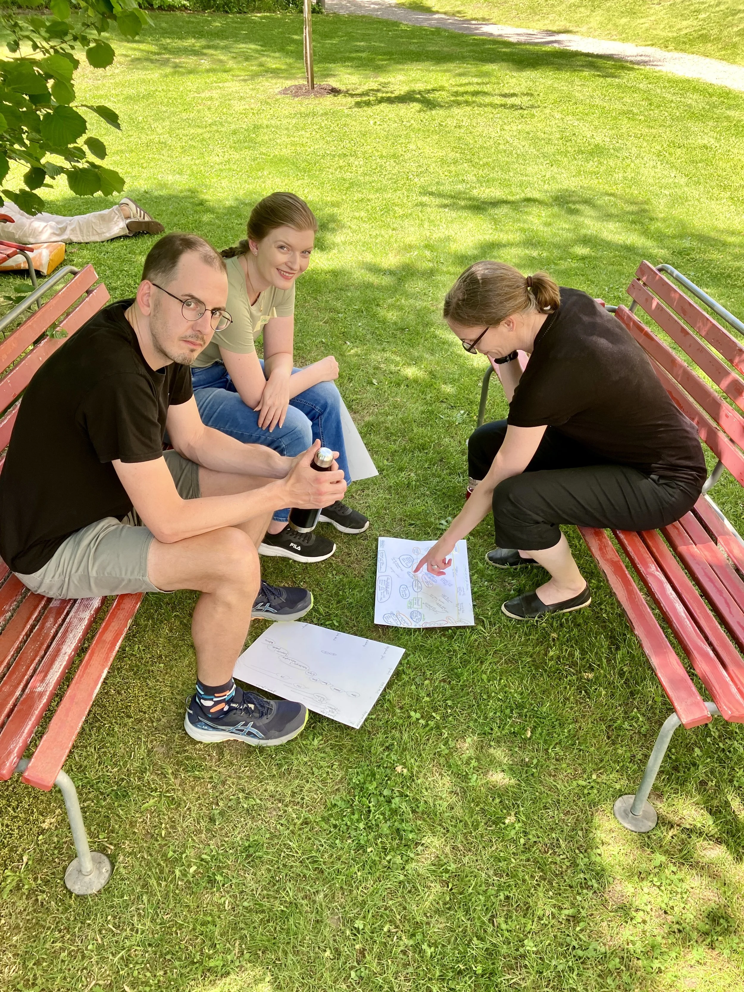 Drei Personen unterhalten sind, auf Bänkli sitzend in einem Park
