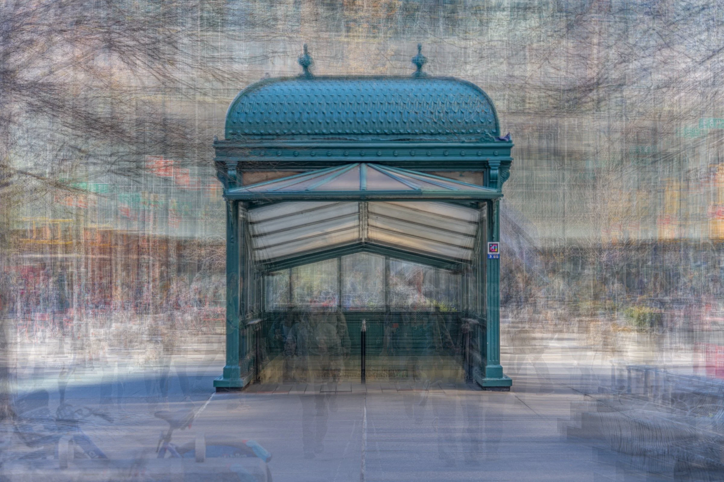 A blue steel and glass bus shelter with a decorative roof, set against a background of leafless trees and a cloudy sky. Astor Place New York City