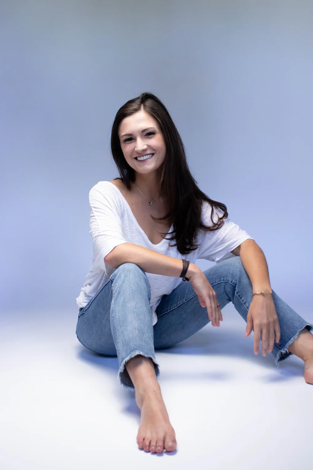 Stephanie smiling, seated against a light blue background