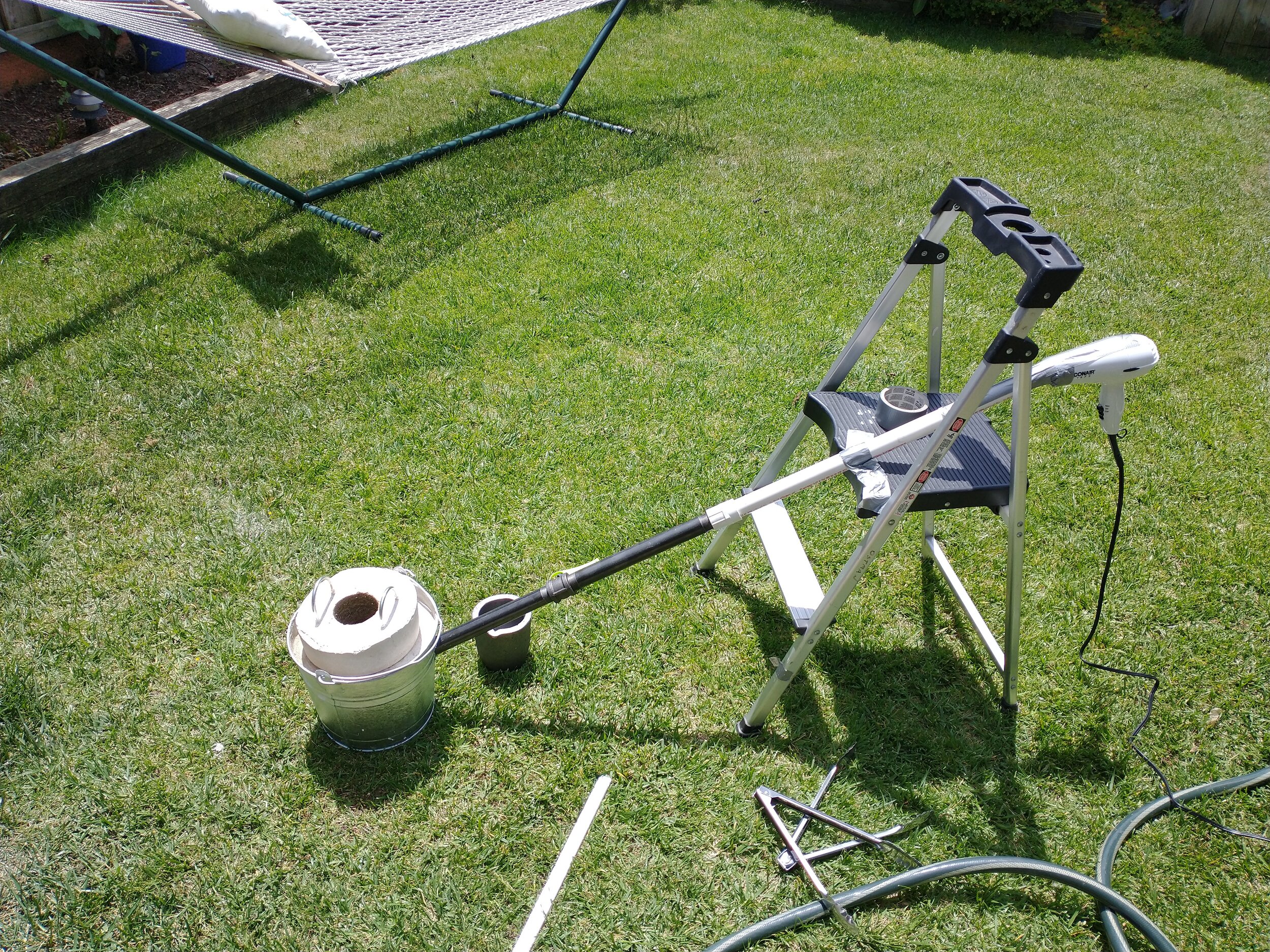 The older setup. The hairdryer attached to the pipe provides airflow, while the charcoal packed around the crucible provides the fuel. To see more about how this earlier version was built, click the image.
