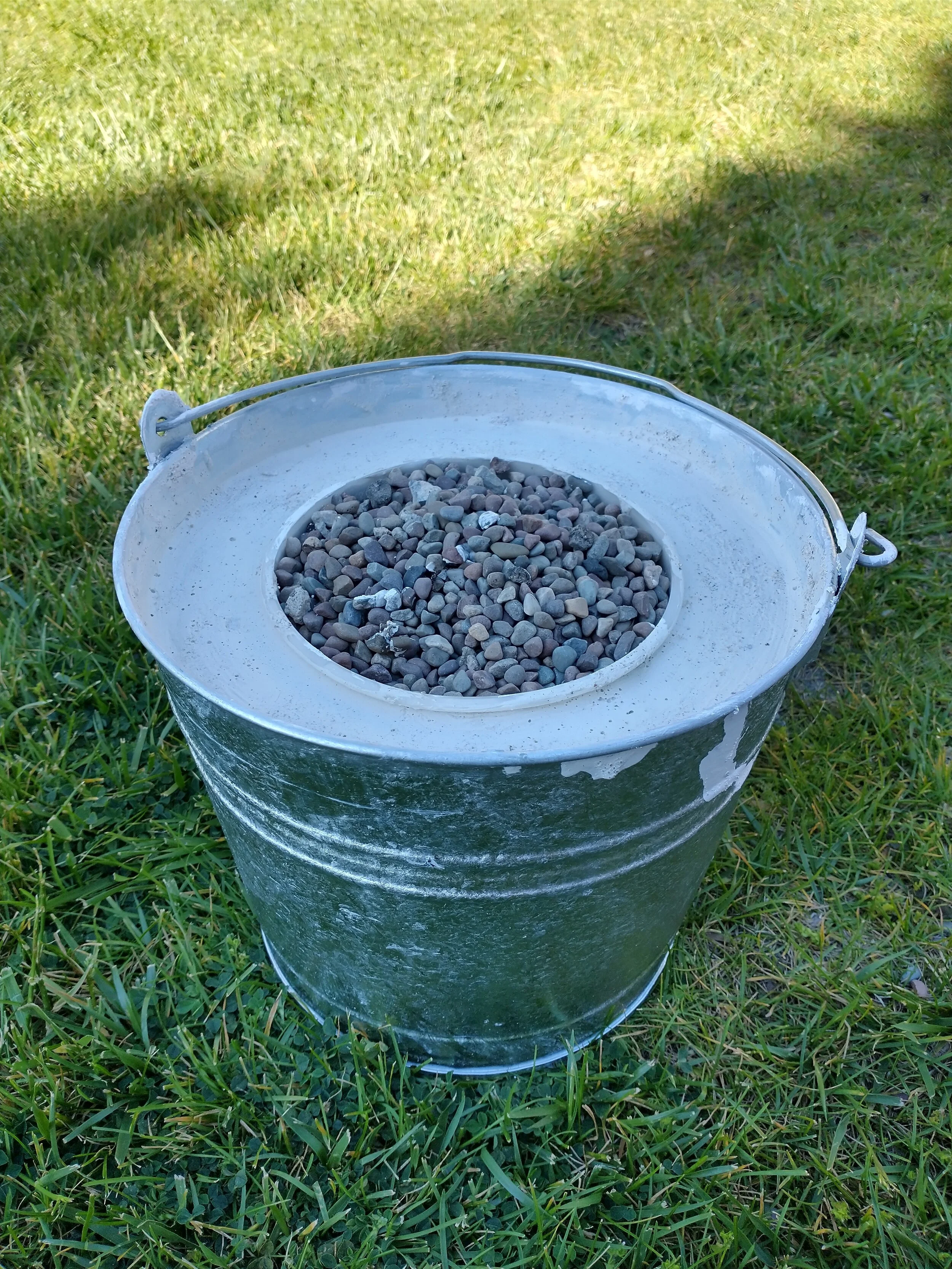 A picture of the foundry while the plaster of Paris is drying. The rocks are to keep the plastic bucket in the right spot as it cures.