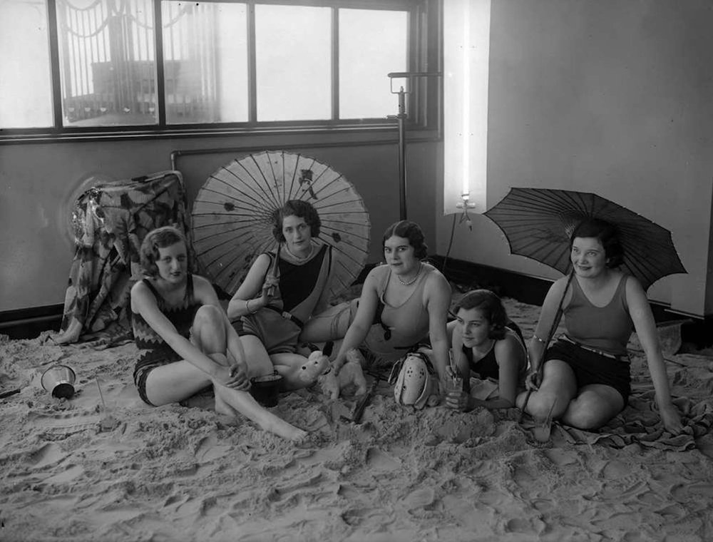  A group of ladies relax on the sandy floor in the solarium of the Tolland Hotel, Bournemouth. 1930. 