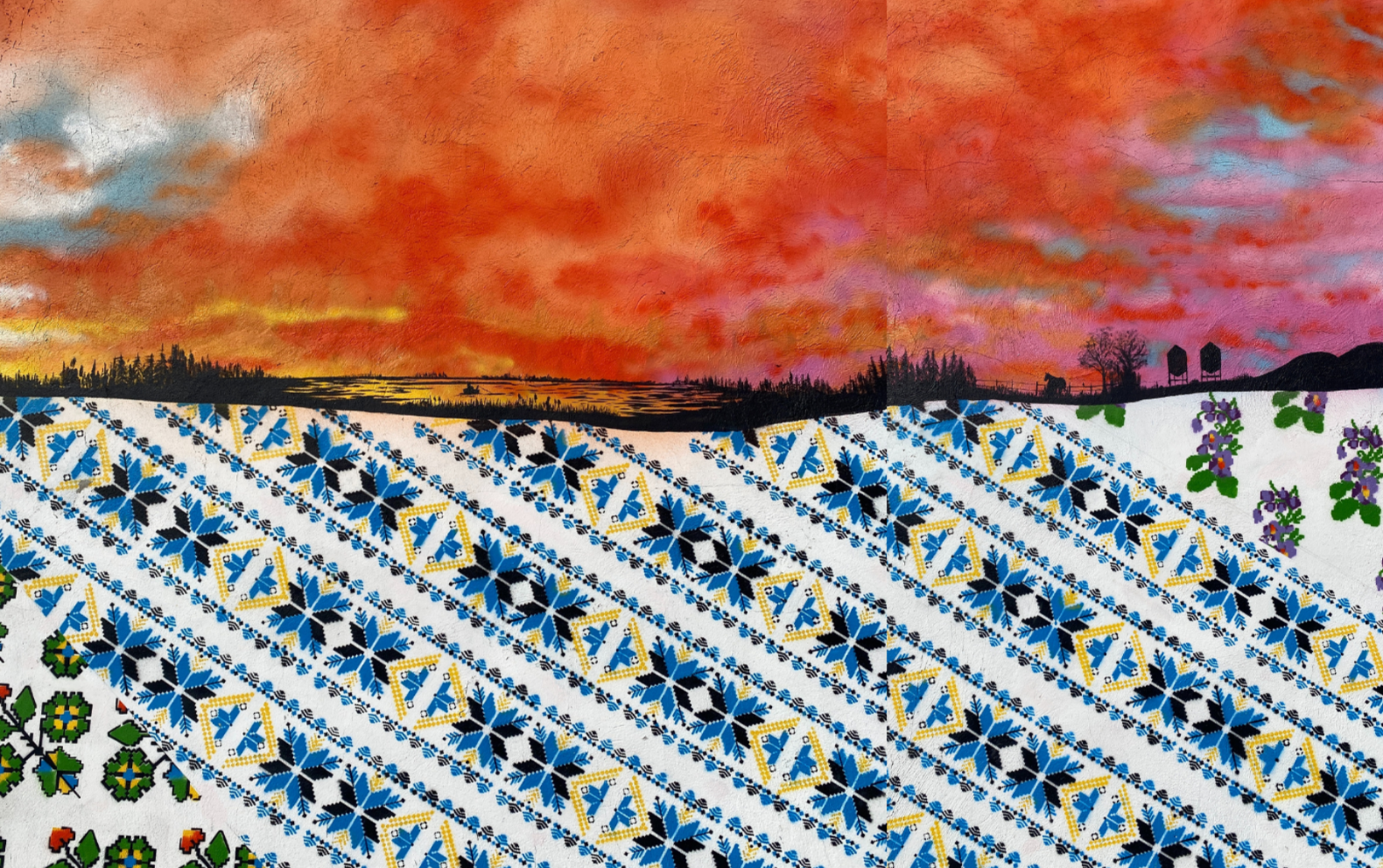 A vibrant sunset with an orange and pink sky over a landscape silhouette, paired with a colorful embroidered textile featuring geometric and floral patterns.