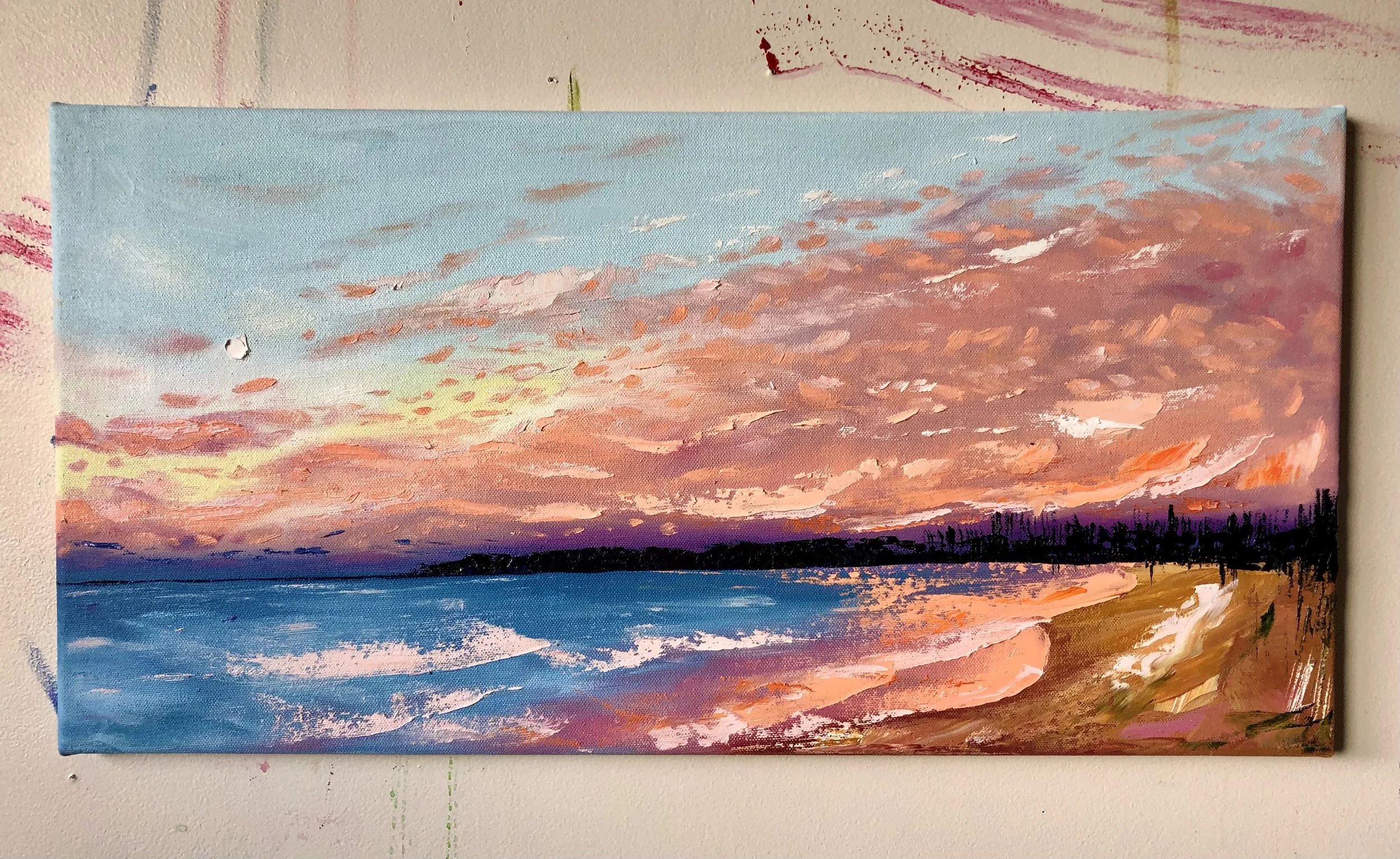 Colorful sunset over the ocean with pink, orange, purple, and blue hues reflected in the water and clouds