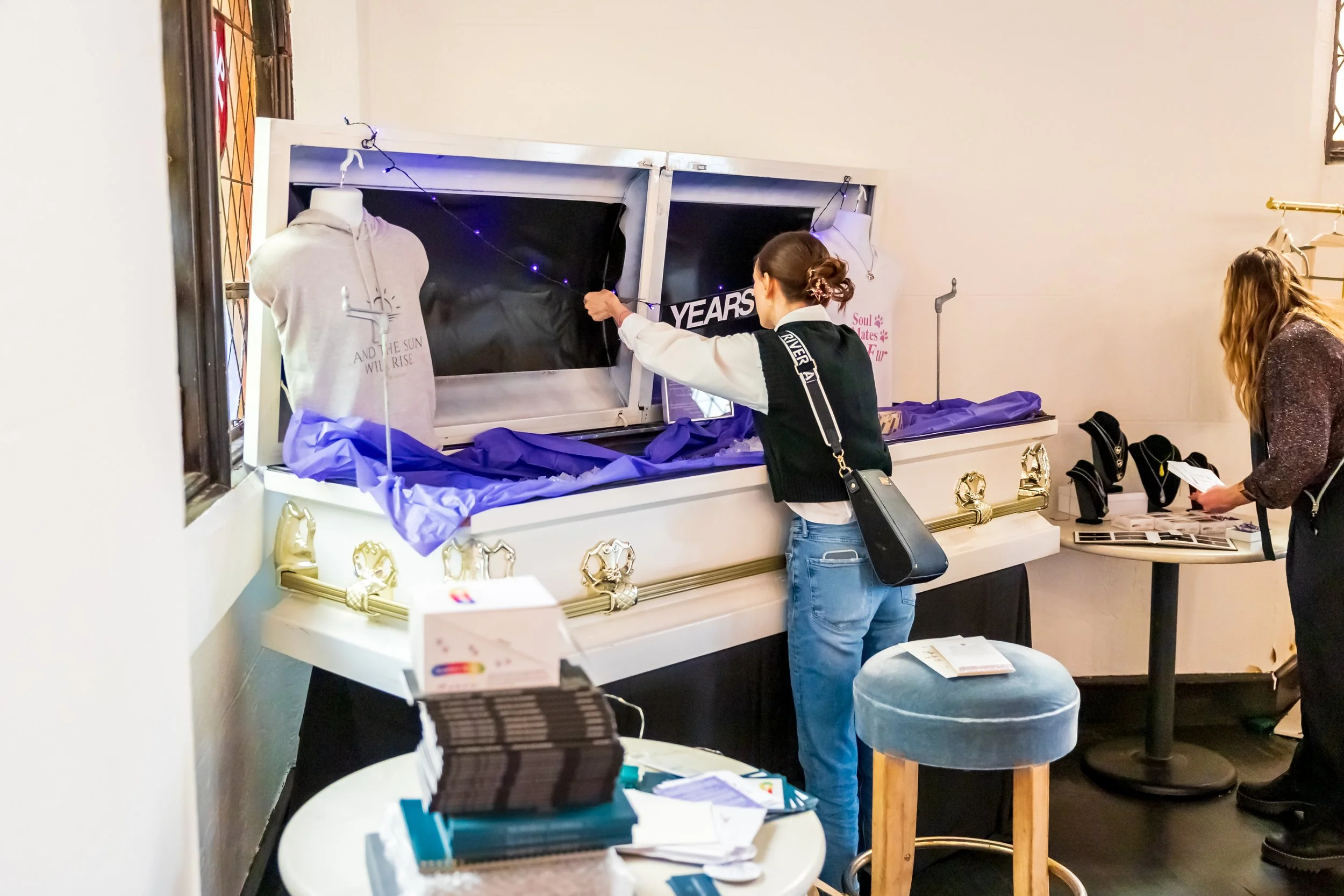A woman looks at jewelry displays and a mannequin with a t-shirt in a jewelry store or exhibition.