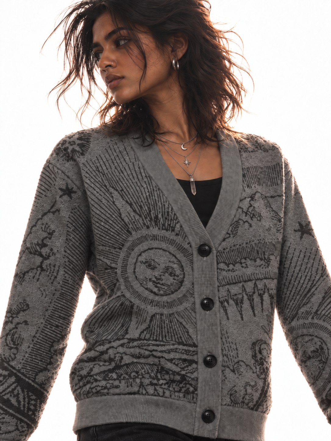 The Anderson cardigan neckline with layered silver necklaces and a hand wearing silver rings