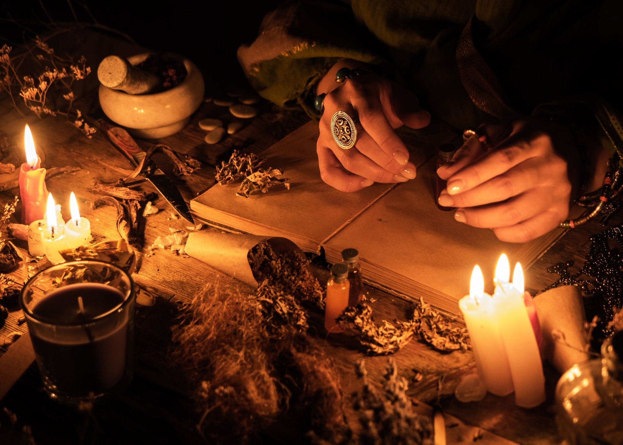 A magical practitioner illuminated by candle light using Madame Creatrix’s Cord Cutting Spell Kit for breaking habits and cutting karmic and cosmic ties and bonds.