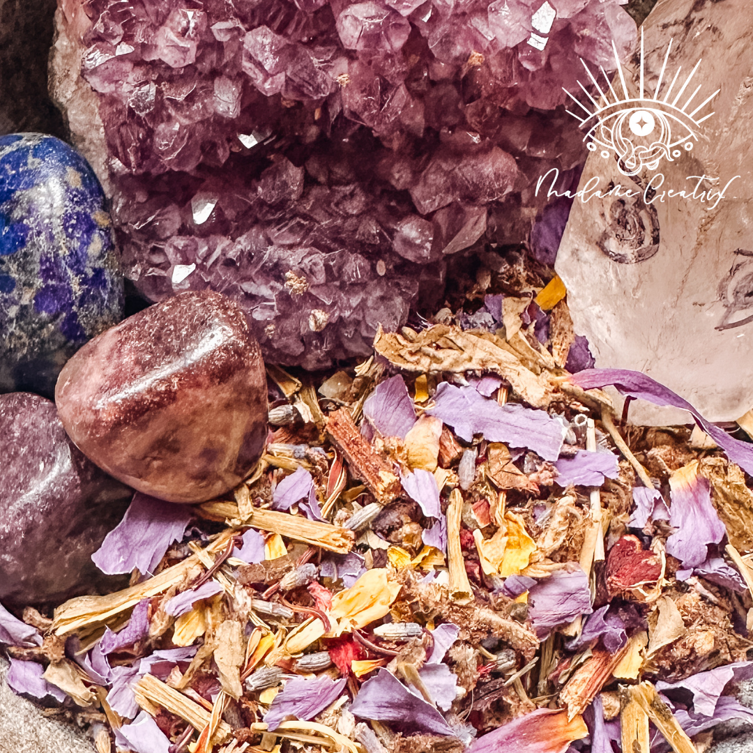 The colorful herbs of the Consorting with Spirits blend sit in a bowl with amethyst, quartz, and tektite crystals.