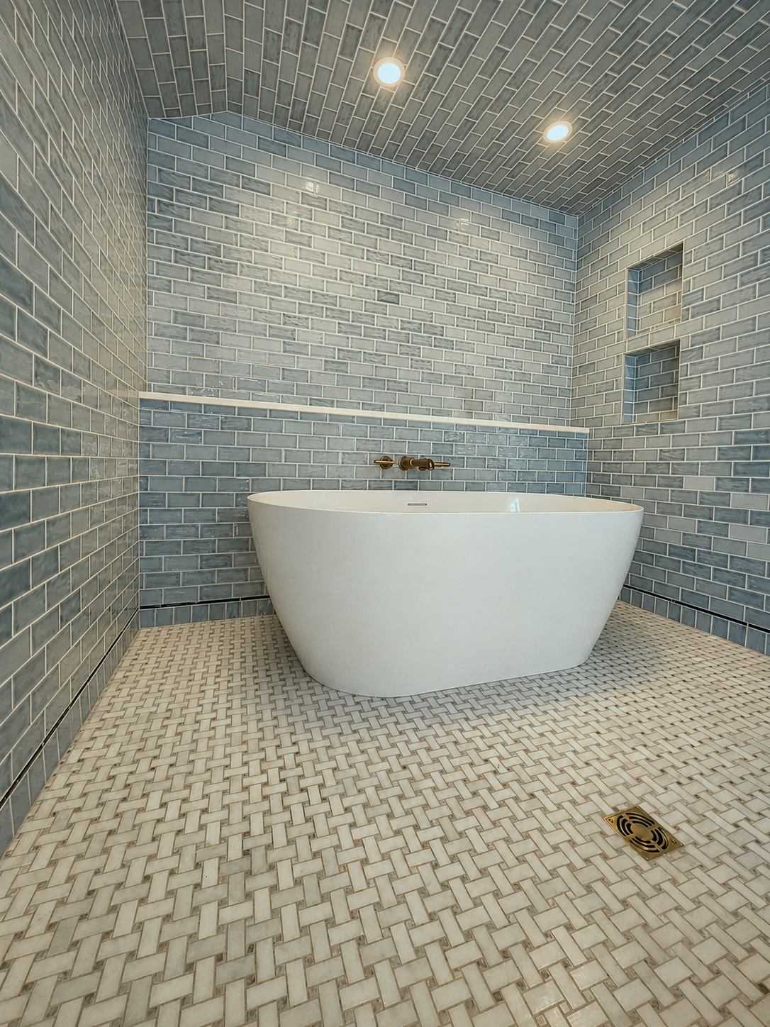 A freestanding tub in a walk-in shower/wet room with a marble ledge that runs the span of the shower.