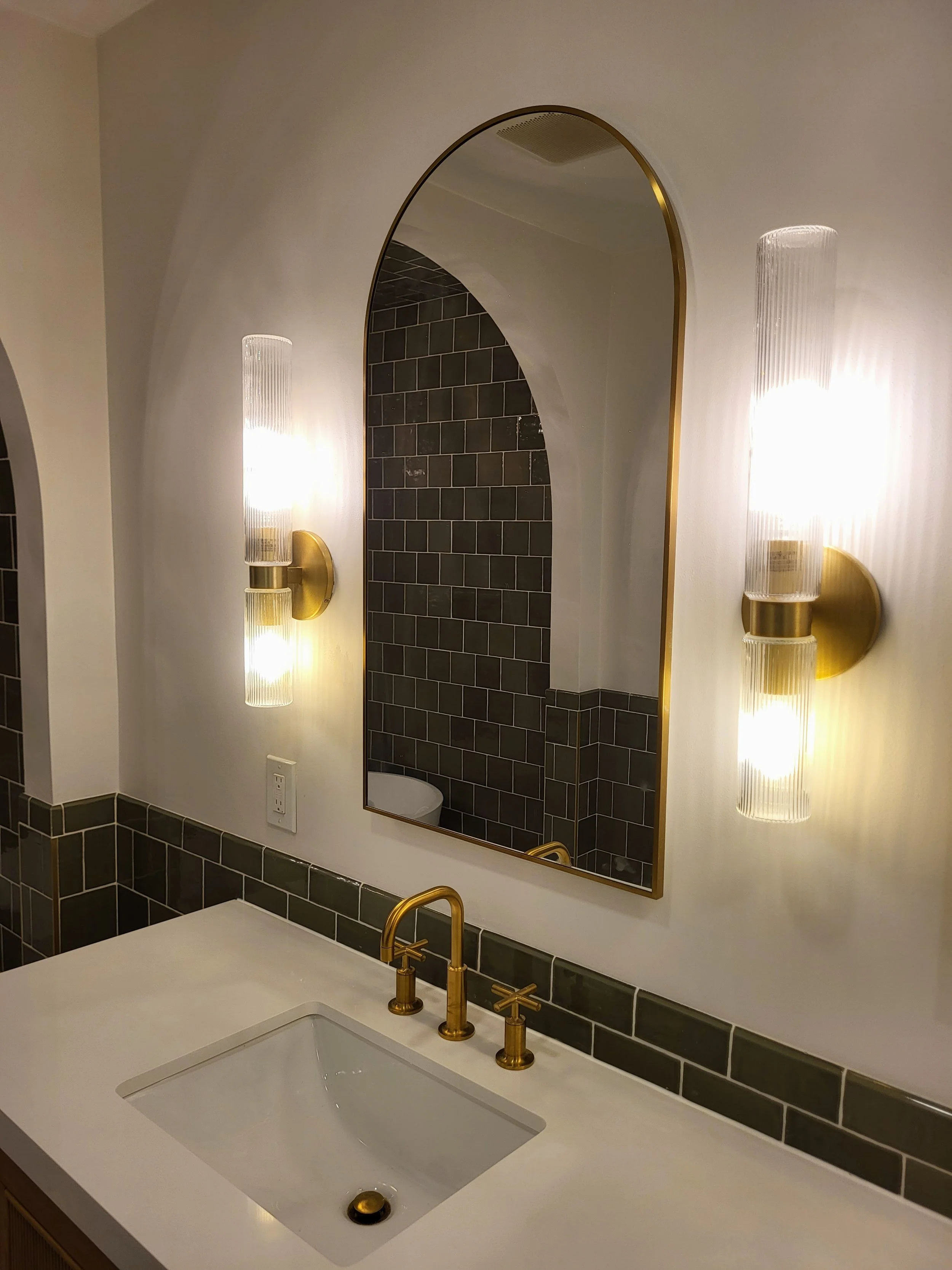 Bathroom vanity and arched medicine cabinet with luxury modern brass finishes.