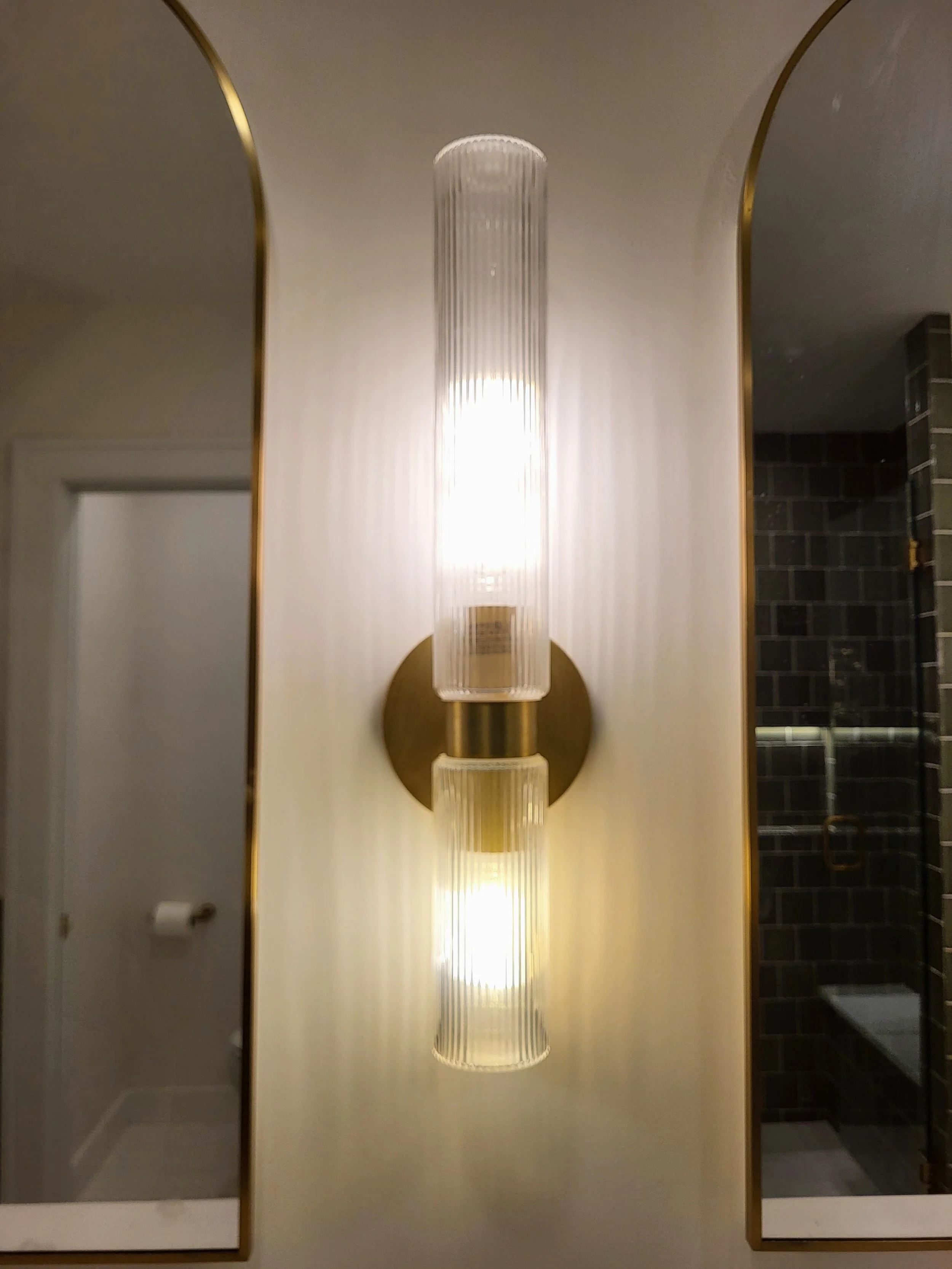 Double lighted wall sconce between mirrors.