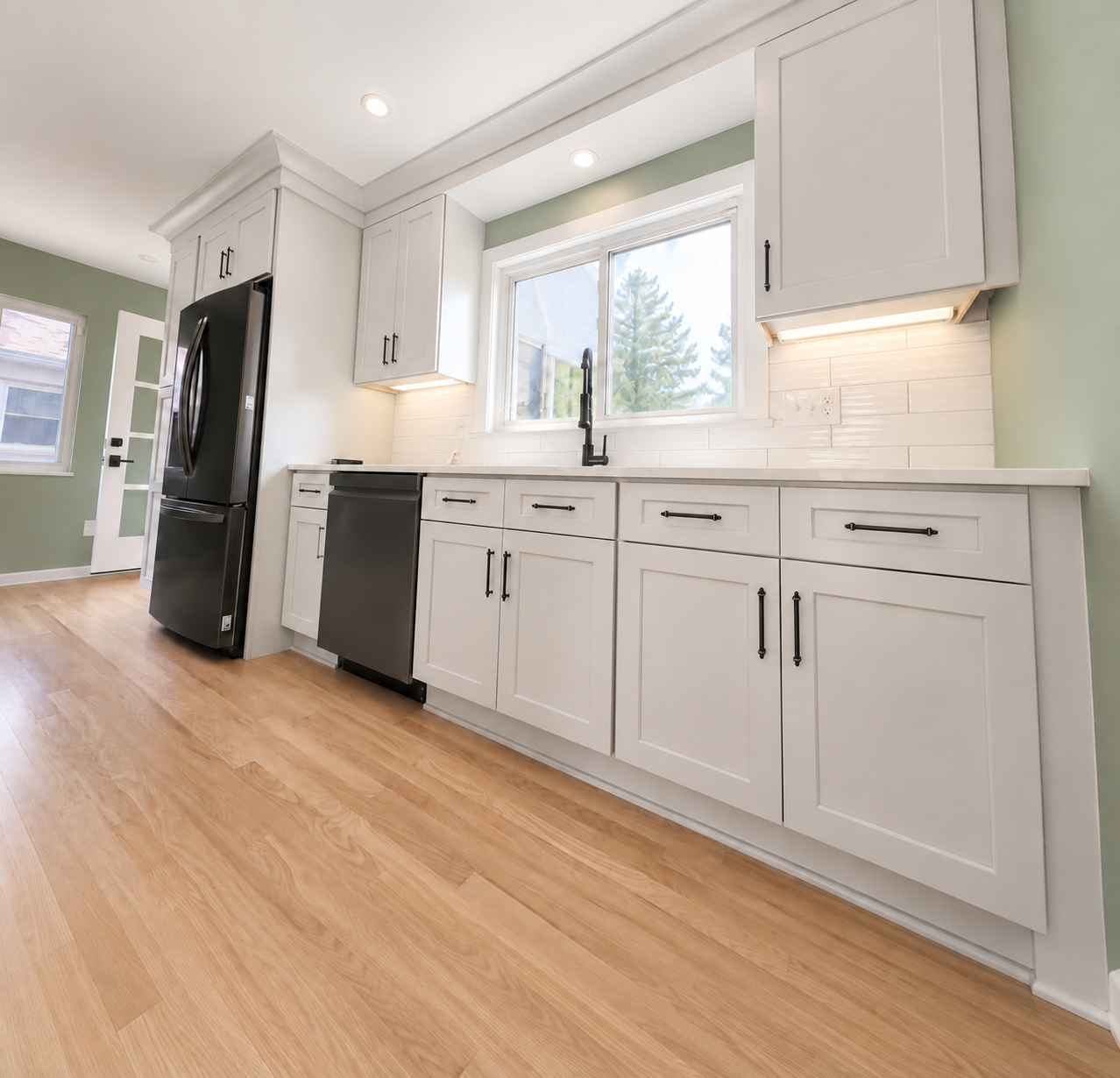 Kitchen cabinets with sink, dish washer, and refrigerator.